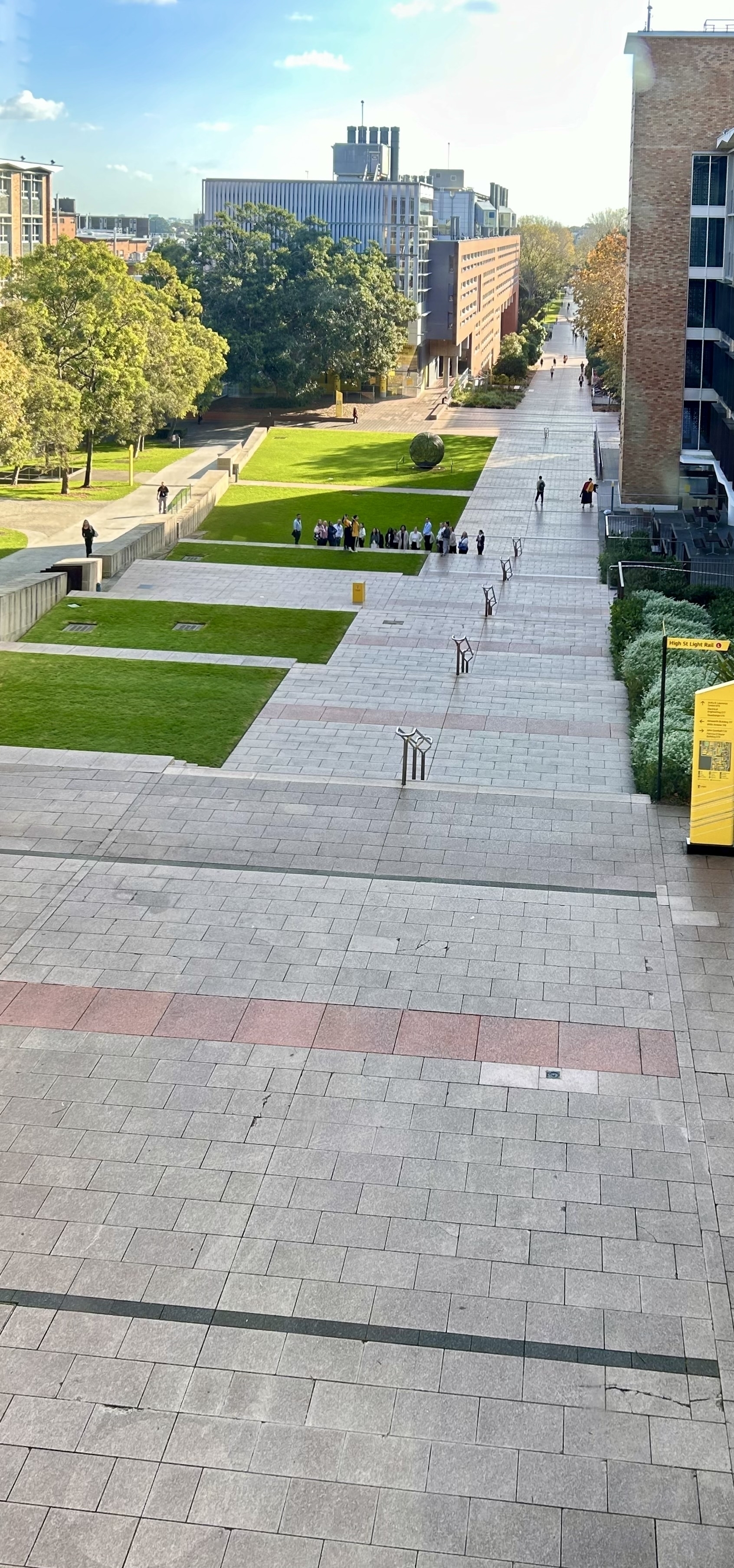 Elevated view of a long walkway at UNSW. People are visible in the distance, flanked by buildings.  