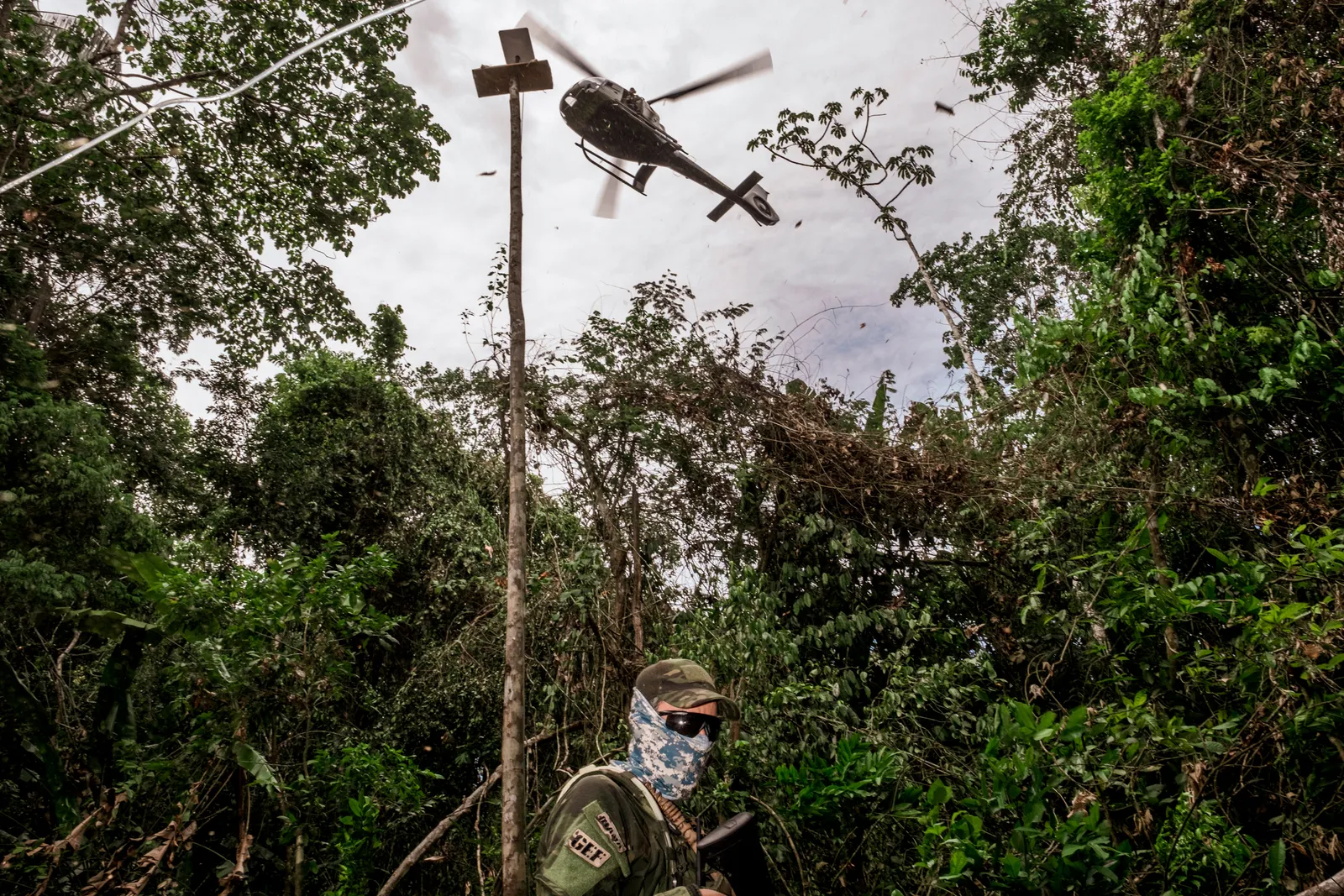 A special forces soldier wearing sunglasses and a face mask with jungle in the background