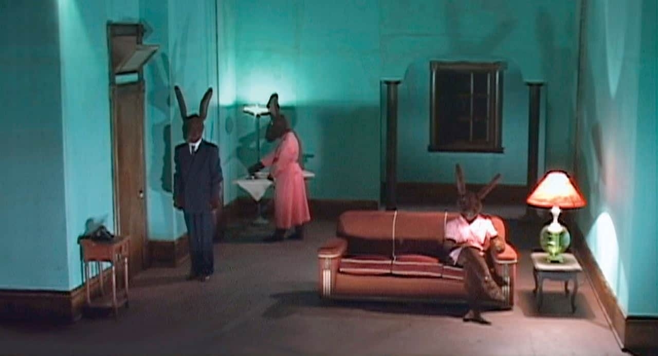 Three humanoid rabbits (humans wearing rabbit suits on an apprent TV sitcom set. These are the rabbits from David Lynch's Inland Empire.