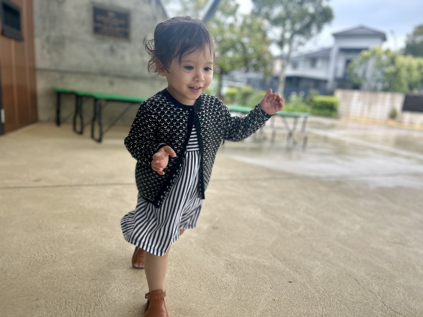 A smiling toddler running with raised hands. 