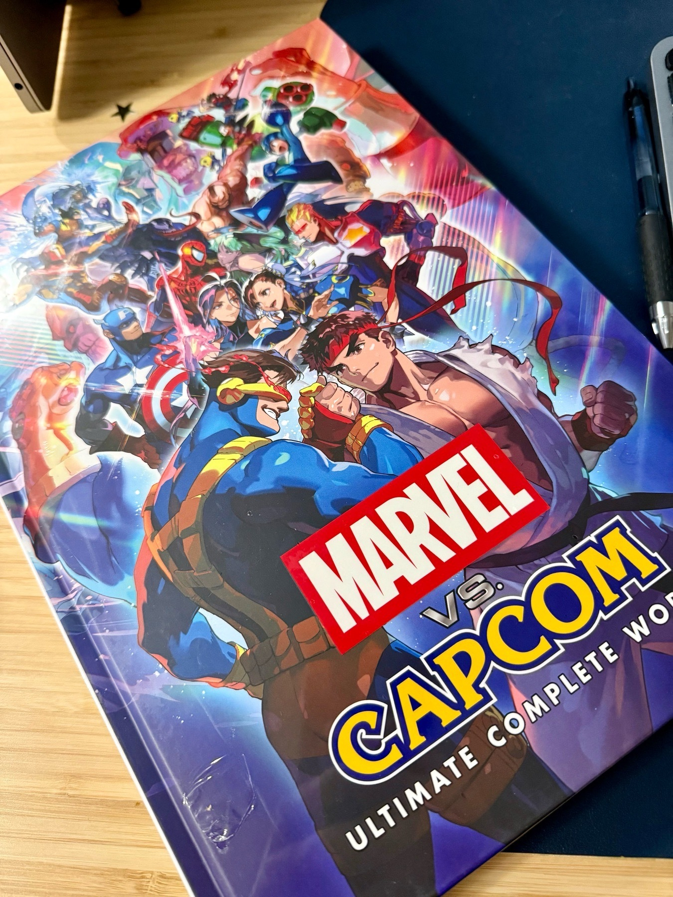 Udon’s “Marvel vs. Capcom: Ultimate Complete Works” hardcover art book, on a desk.