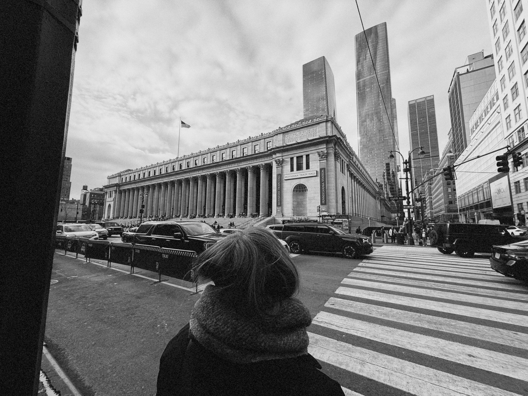 A woman standing at a crosswalk heading to Moynihan Train Hall in New York City.