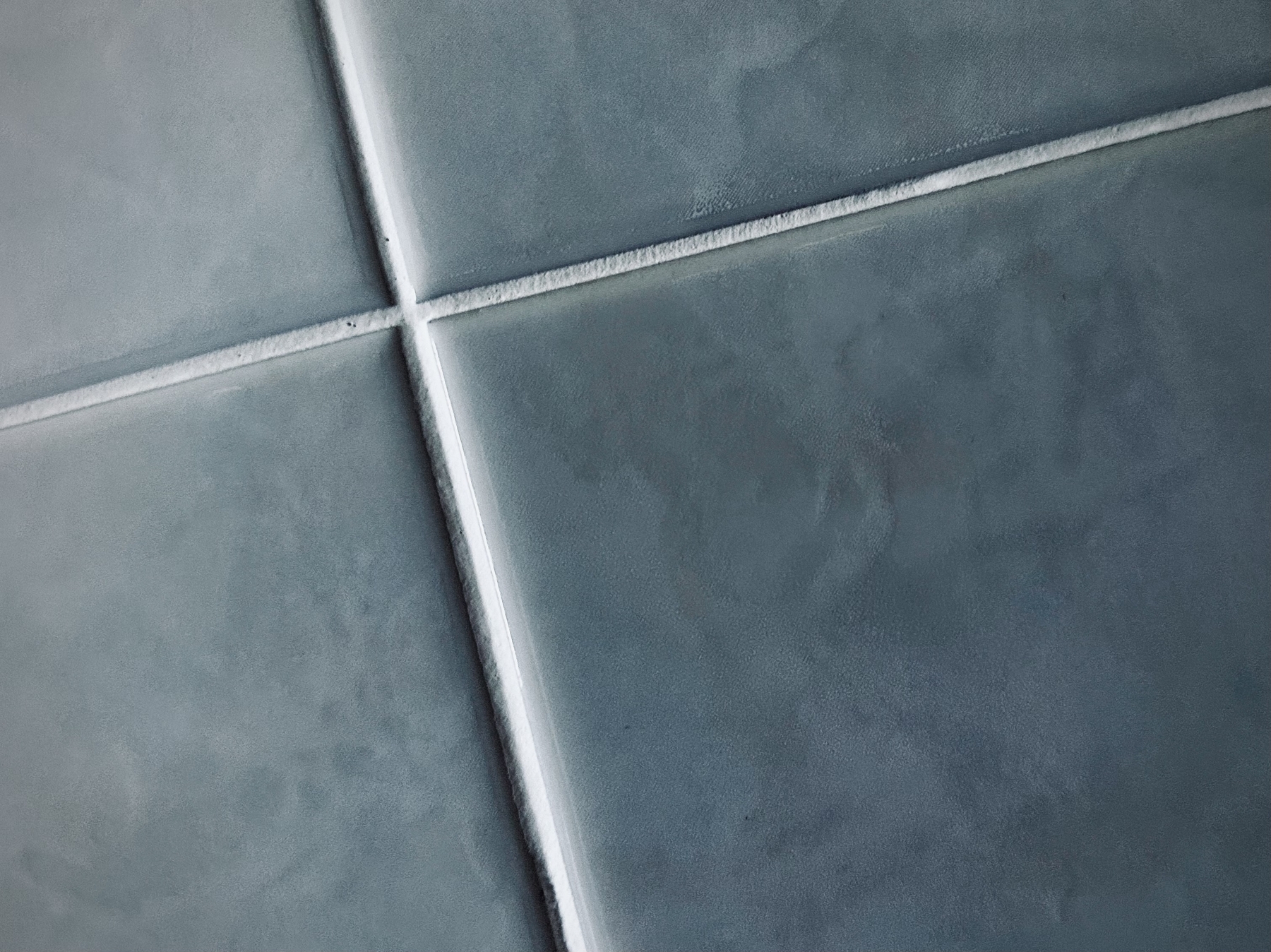 A high contrast close up of the subtle textures in some large white tiles.