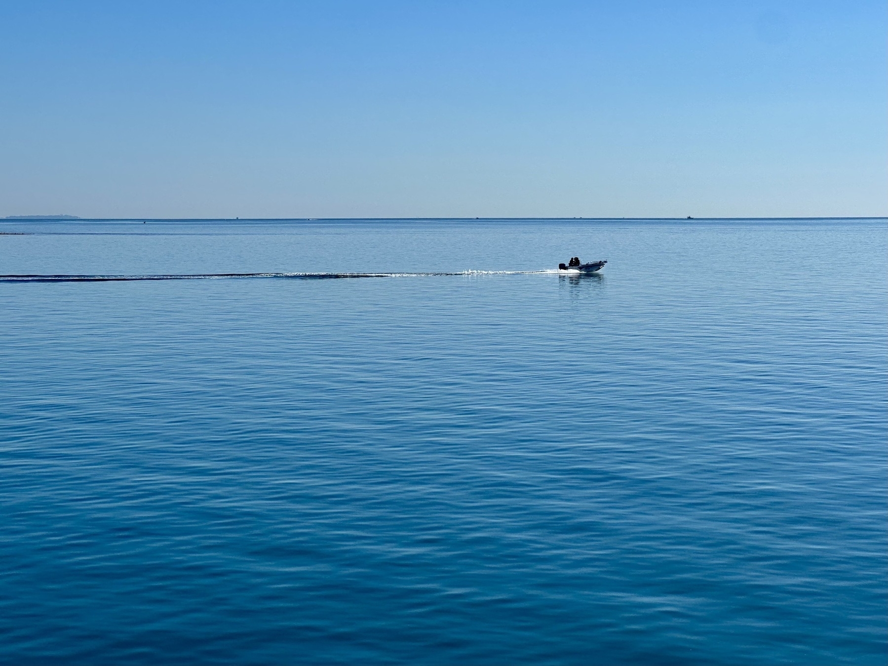 A small tinny zipping out into Moreton Bay for a spot of fishing. Clear blue skies above almost glassy ocean conditions.