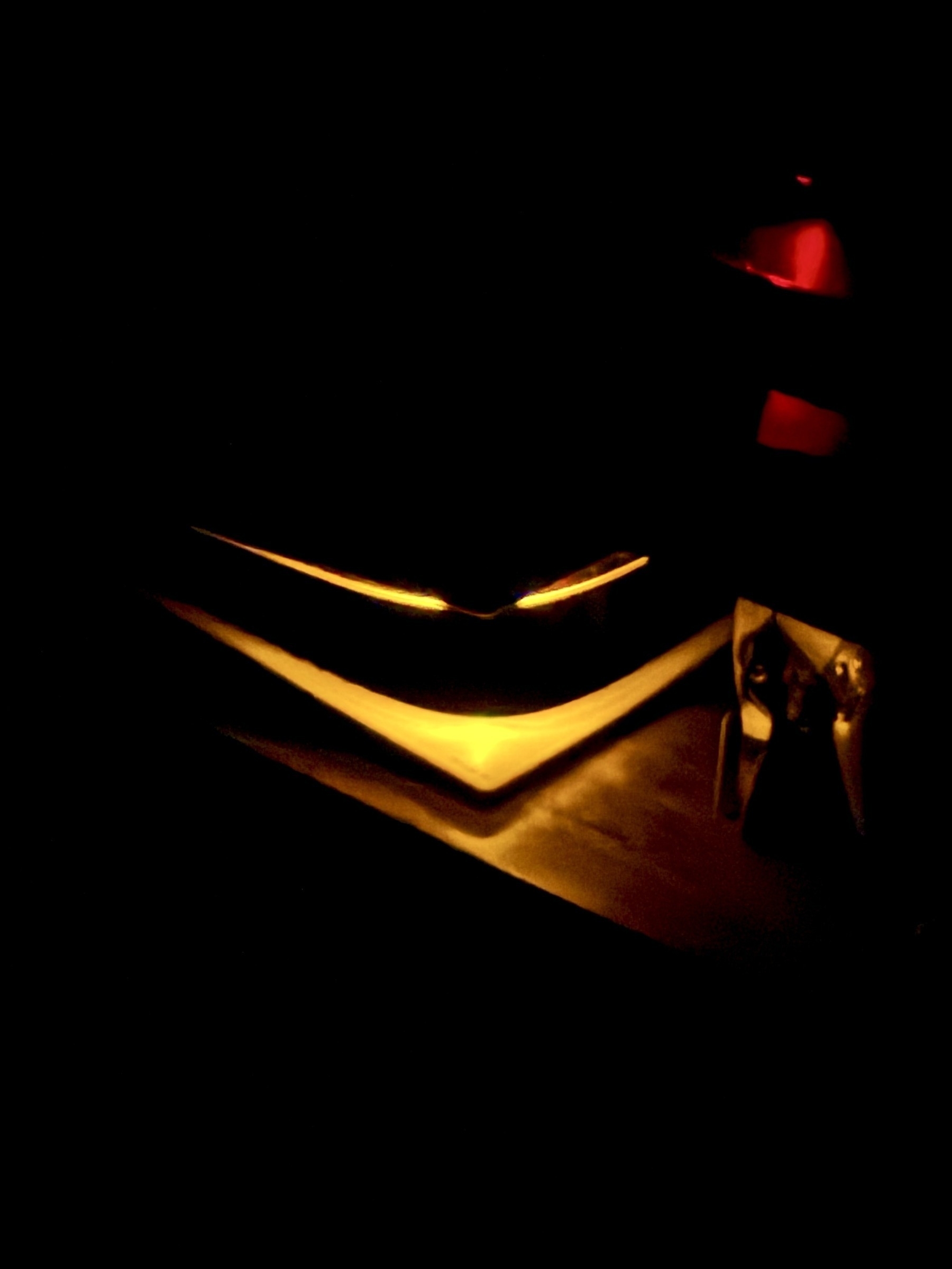 The corner of a sleeping PS5, a glowing orange grimmace in the dark.