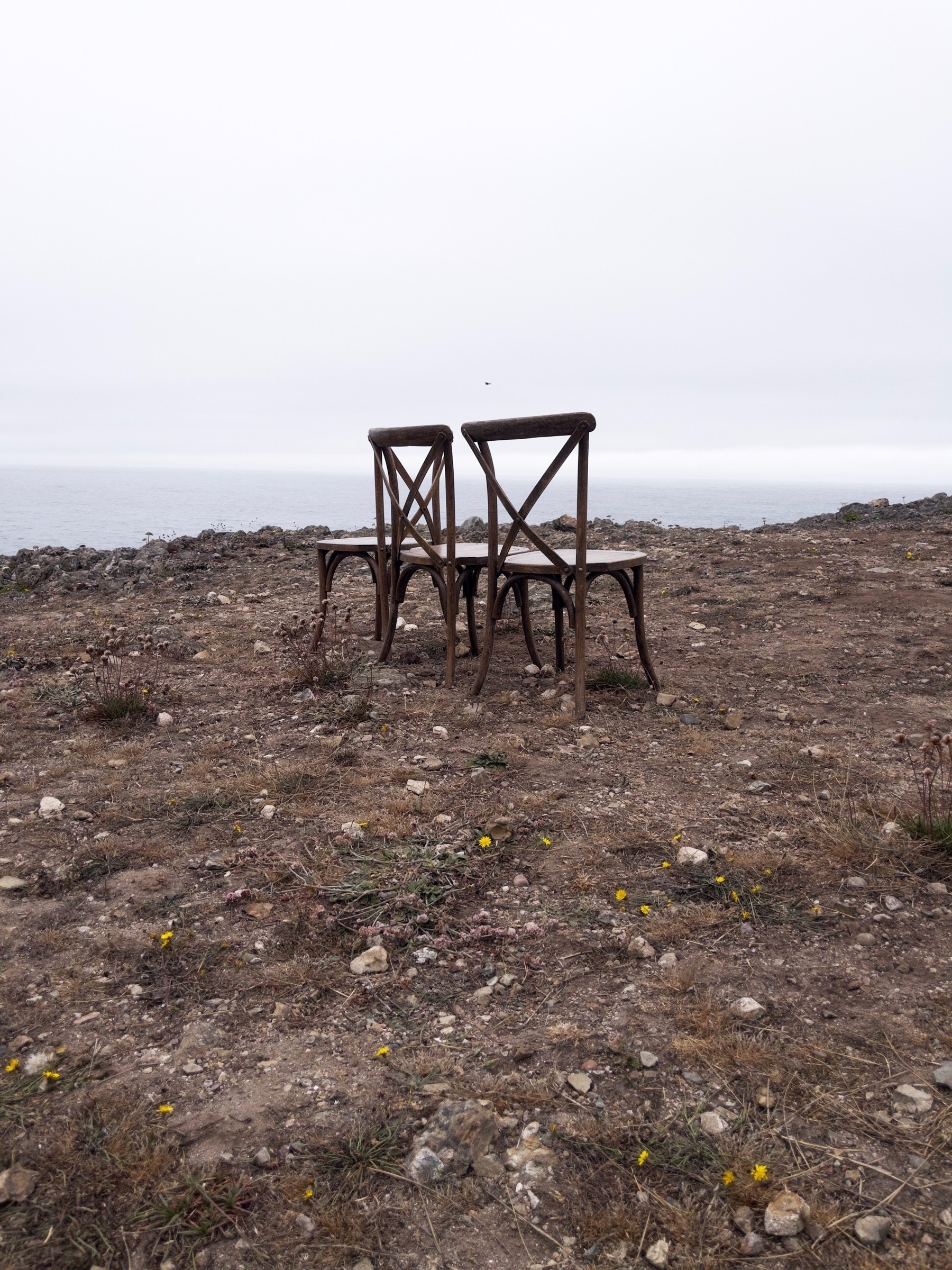 Three chairs sitting on a bluff overlooking the ocean