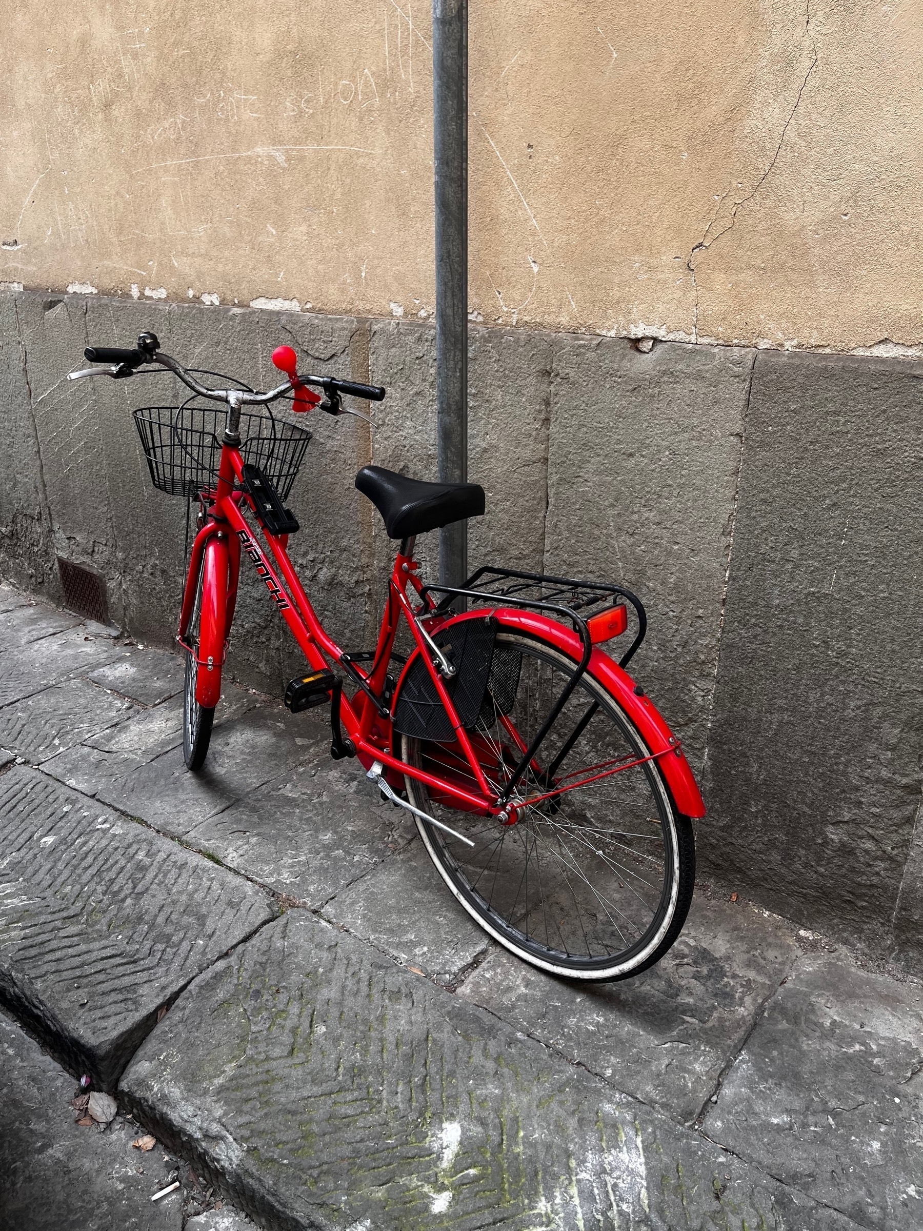 A red bicycle leaning against a wall in Florence, Italy