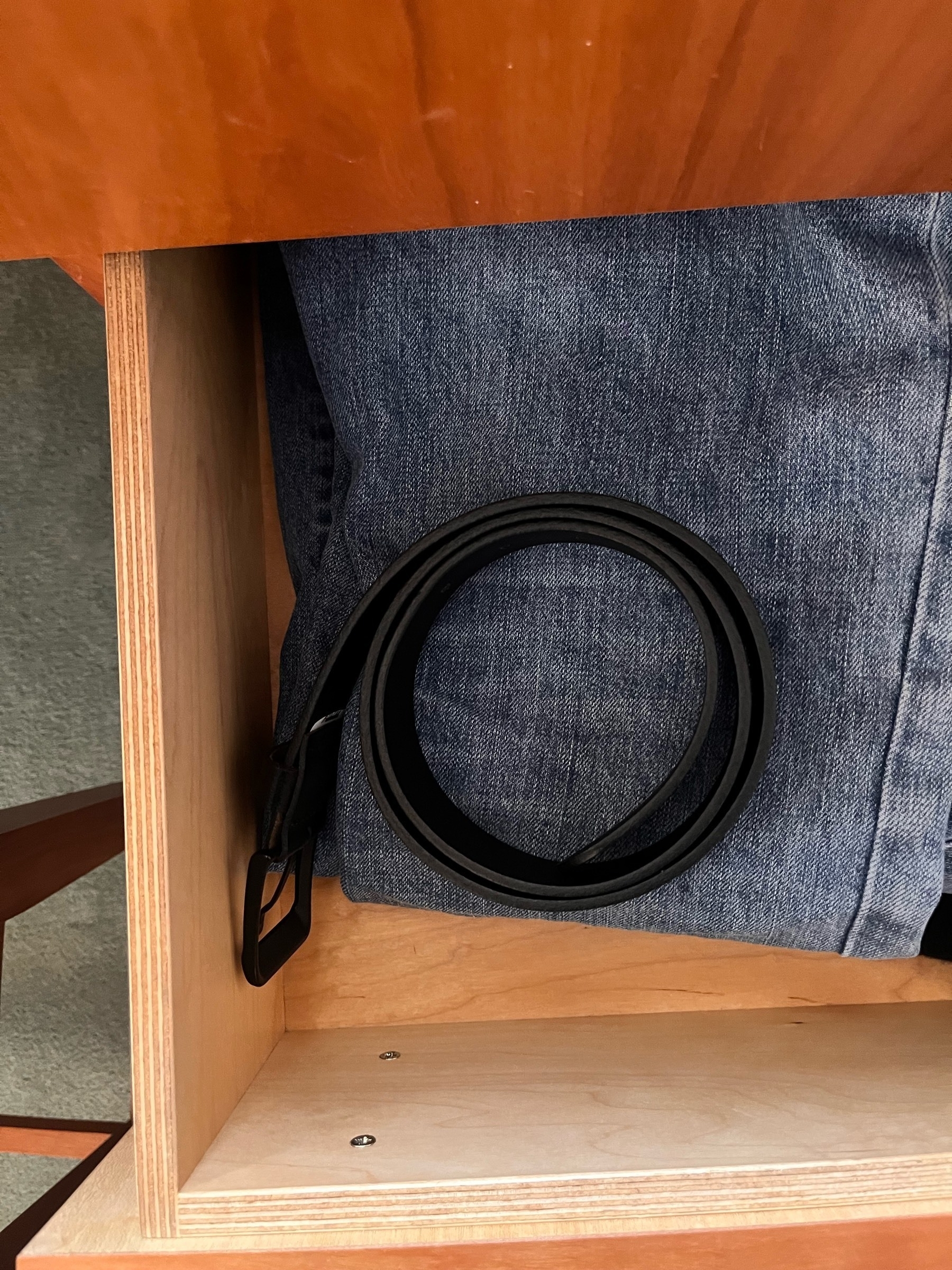 Belt sitting on a pair of jeans in a draw