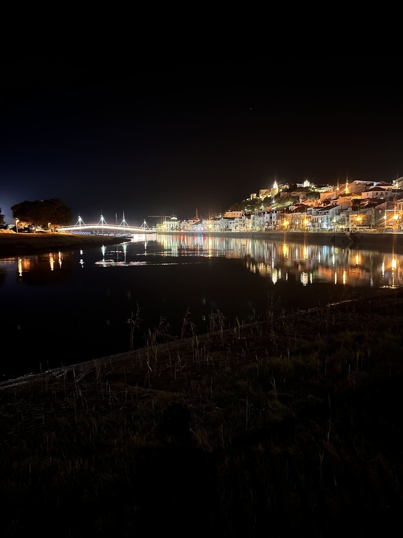 The town of Alcácer do Sal in Portugal at night time, taken from by the river looking up the hill, all lit up