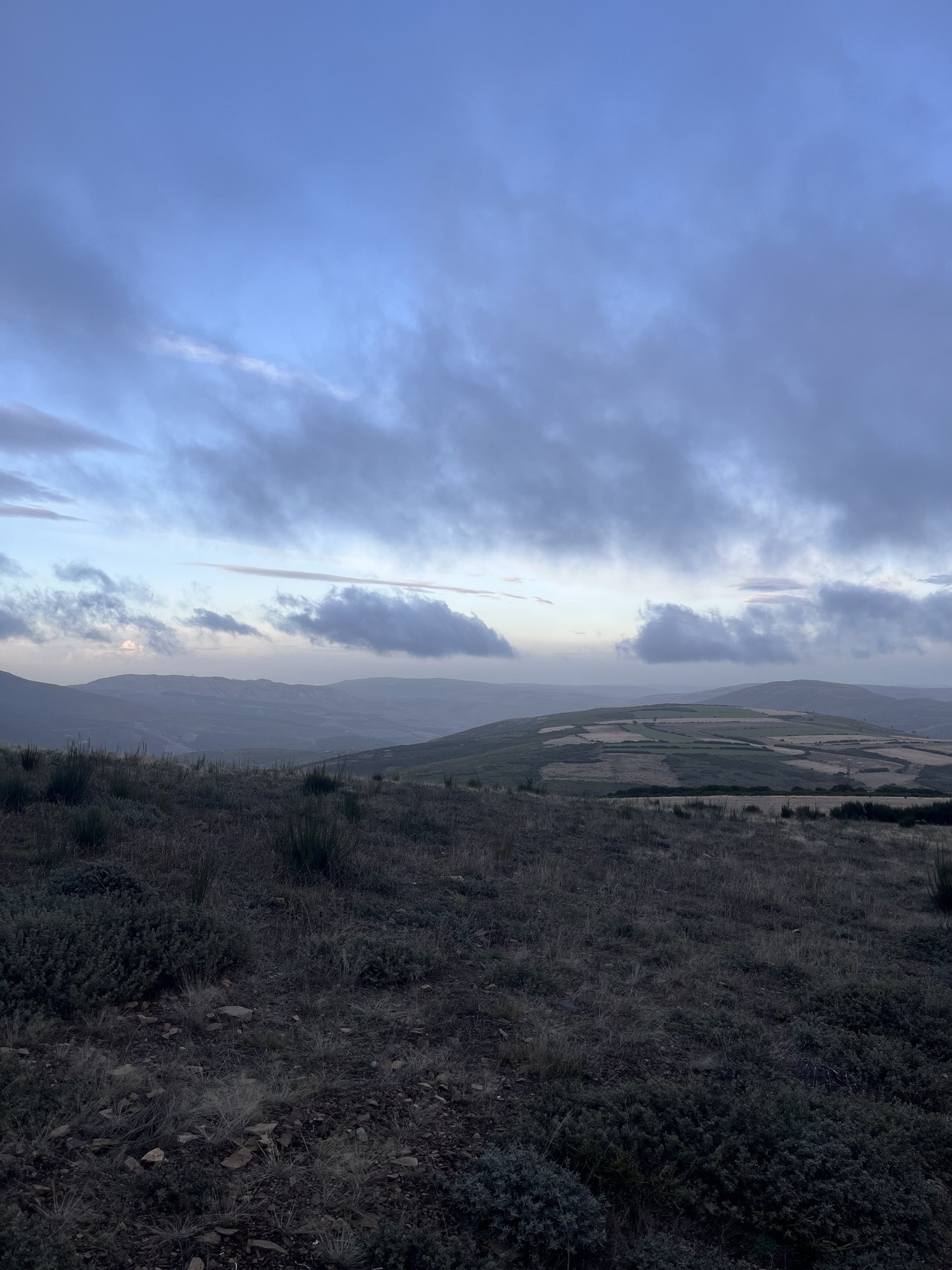 A vast, open landscape with rolling hills under a cloudy sky.