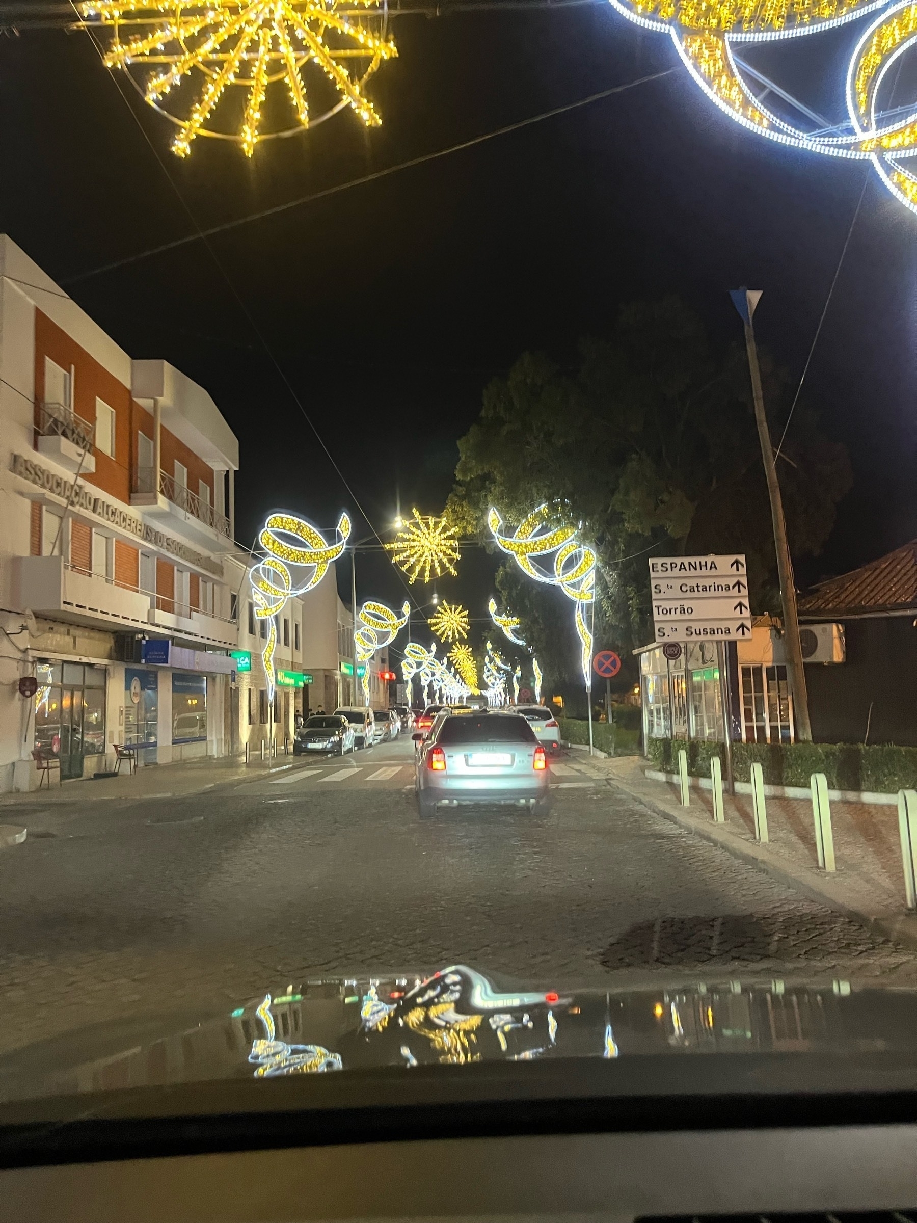 Cars sit in a traffic jam underneath decorative festival lights.