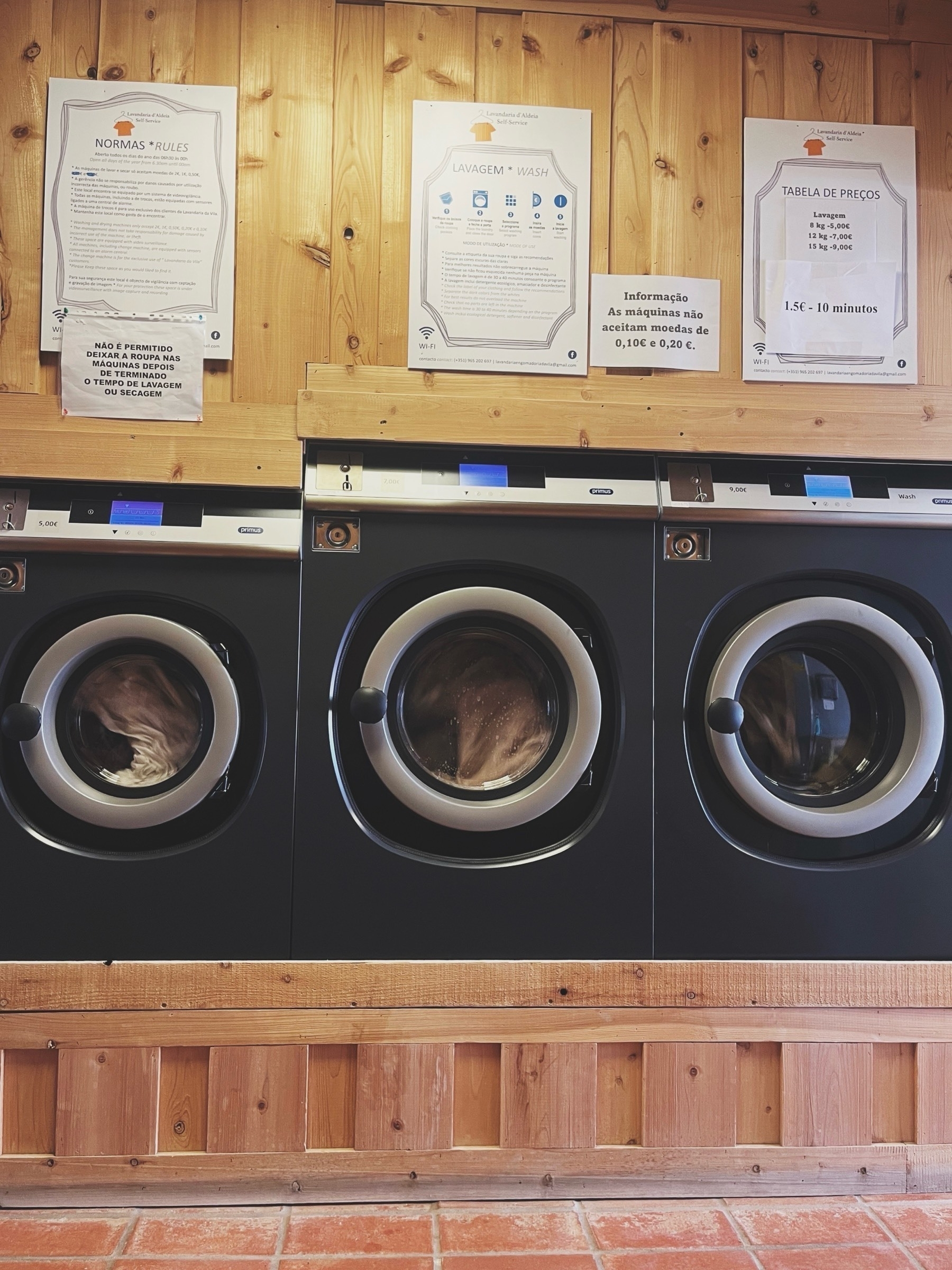 Three full washing machines in a laundromat.