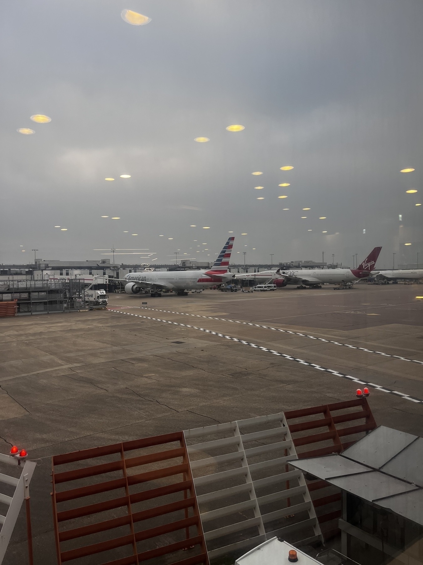 Several airplanes are parked at an airport terminal on a cloudy day.