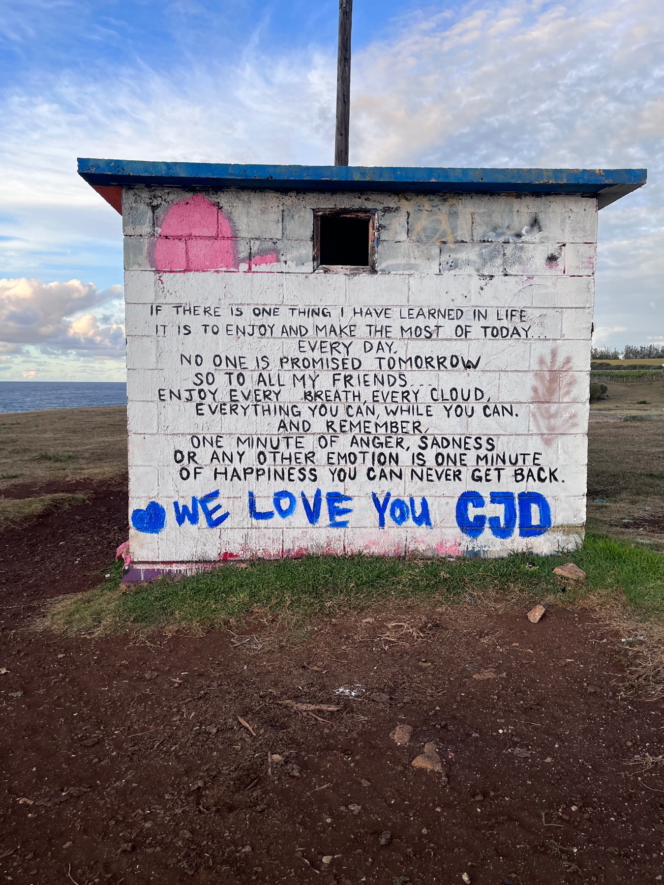 A small building features a painted message about enjoying life and cherishing each moment.