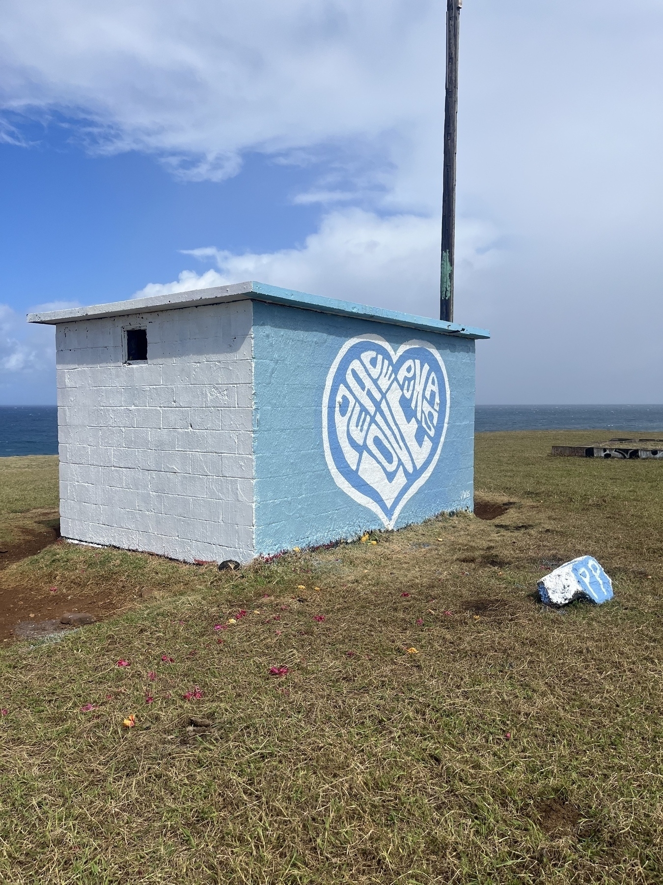 A small white and light blue building with a heart-shaped Peace and Love