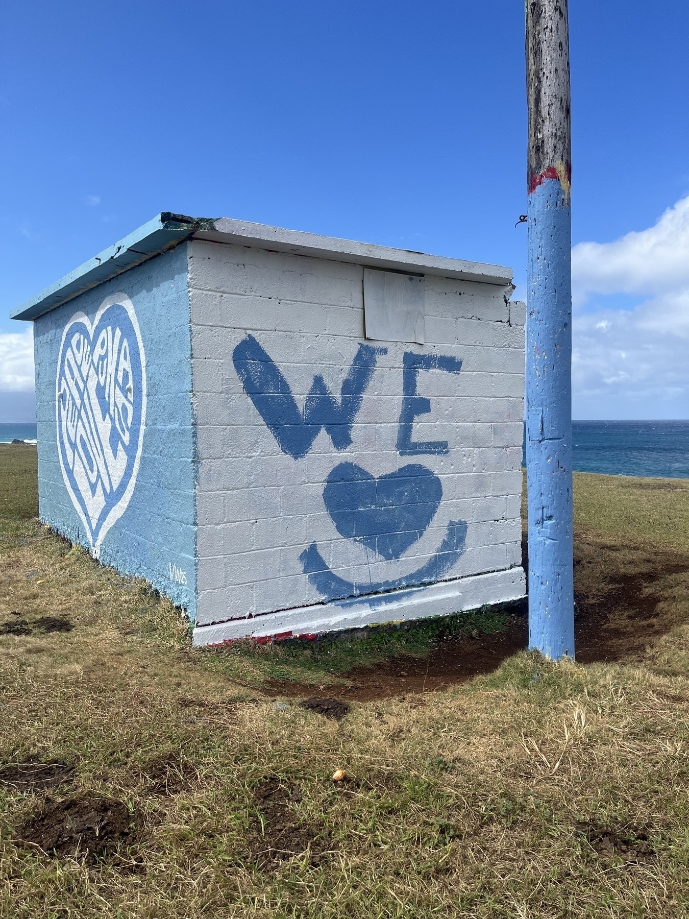 A small white and blue building with graffiti art saying WE