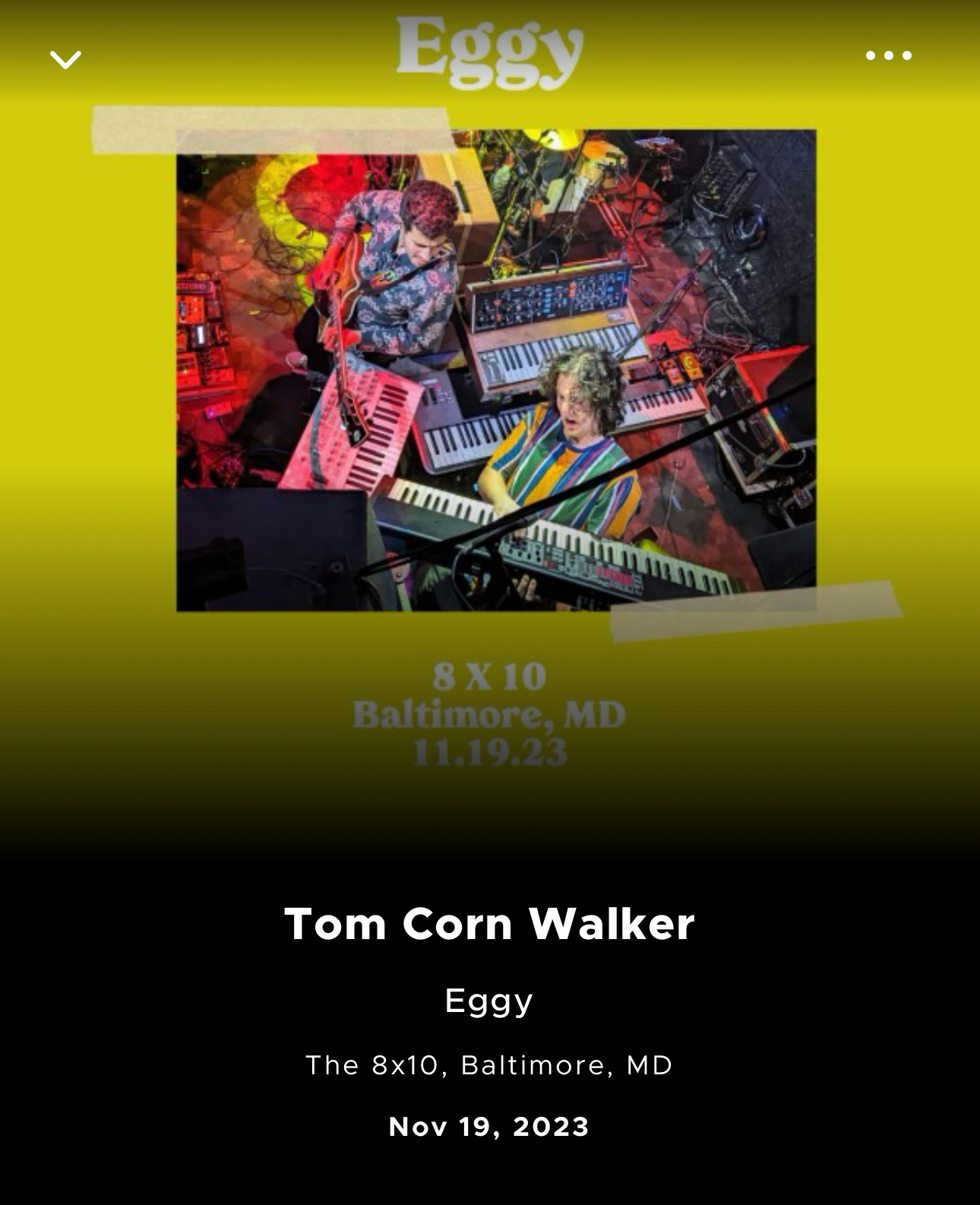 Event promotion image featuring two musicians surrounded by keyboards and synthesizers, with the band name “Eggy” at the top. Text on the image indicates artist “Tom Corn Walker” performing at “The 8x10, Baltimore, MD”