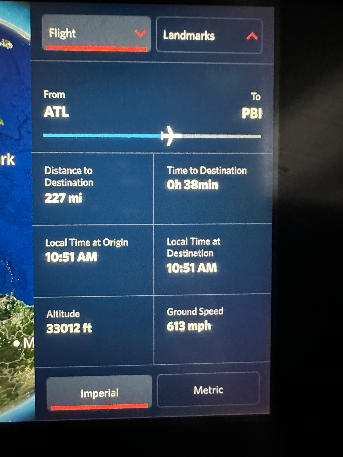 In-flight entertainment screen displaying flight information: Origin ATL, Destination PBI, 227 miles and 38 minutes to destination, local time at both origin and destination 10:51 AM, altitude 33,012 feet, ground speed 613 mph