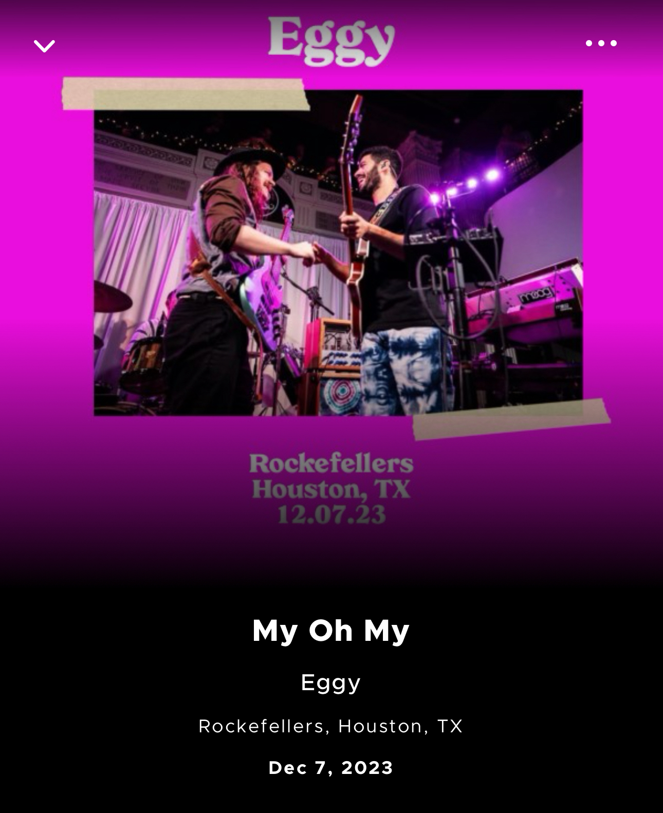 An image of two musicians from the band Eggy performing on stage at Rockefellers, Houston, TX on December 7, 2023. The background features purple lighting and part of a drum set. The musicians are playing guitars and facing each