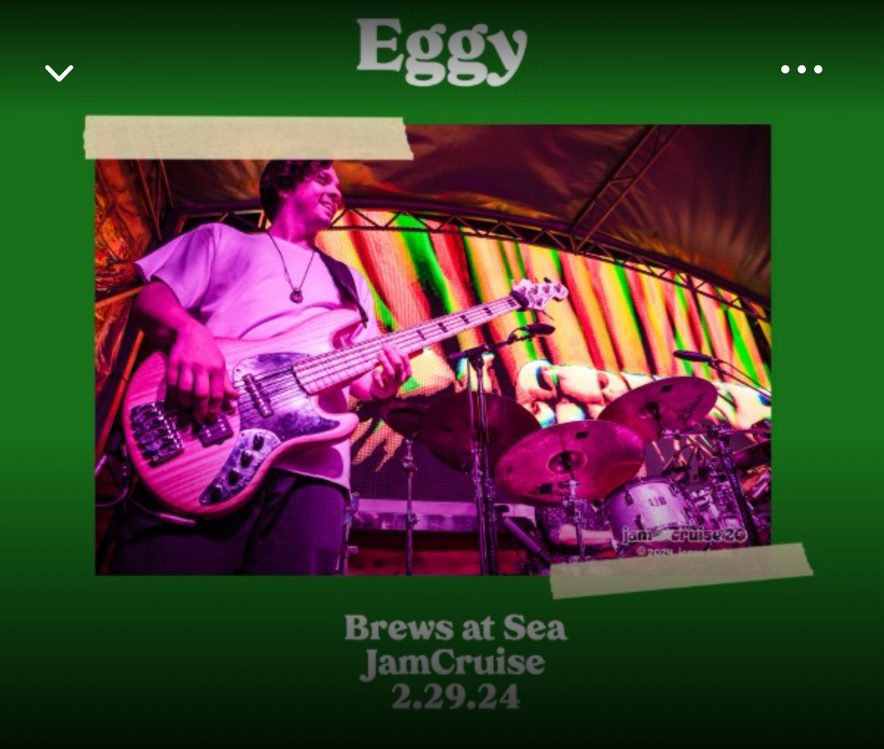 A bassist performing on stage with colorful stage lighting, in front of a drum set with “JamCruise” visible on the drum. The event is labeled “Brews at Sea JamCruise 2.29.24”