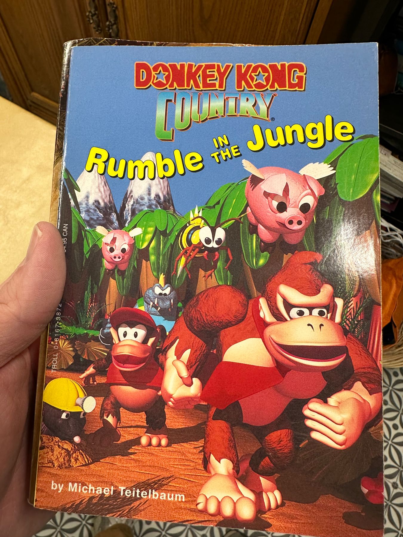 A book cover for “Donkey Kong Country: Rumble in the Jungle” featuring various characters from the Donkey Kong series, including Donkey Kong and Diddy Kong, against a jungle backdrop.
