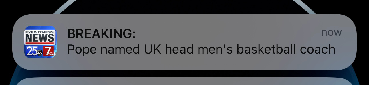 A notification on a smartphone screen from “Eyewitness News” with the text “BREAKING: Pope named UK head men’s basketball coach.