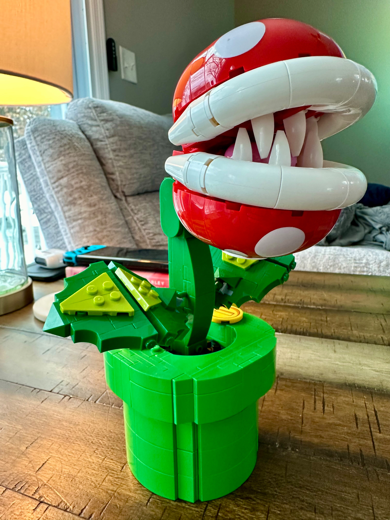 A LEGO model of a Piranha Plant from the Super Mario series, with a red head, white mouth, sharp white teeth, set in a green warp pipe.