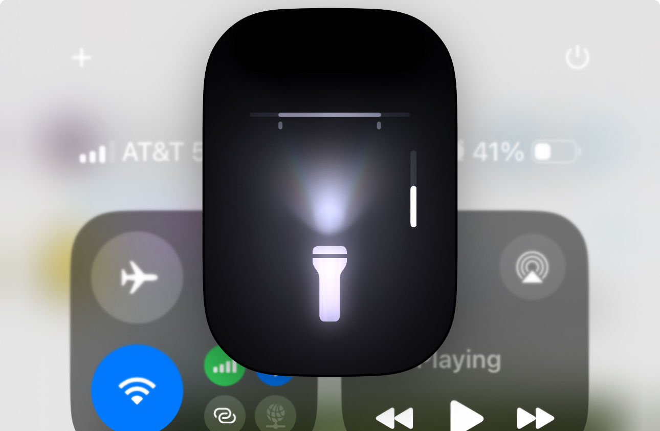 The image shows the flashlight brightness adjustment interface on an iPhone’s Control Center screen. The flashlight icon is illuminated, with the brightness slider positioned to the right. Other Control Center icons and indicators for Wi-Fi, airplane mode, and media playback are partially