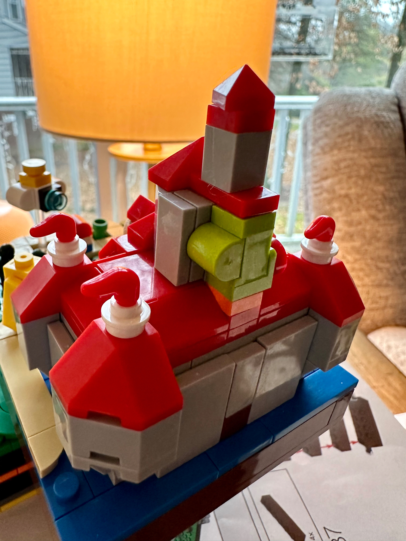A colorful structure made from building blocks, resembling a whimsically designed castle with red rooftops, a central tower, and various shapes and sizes of blocks.