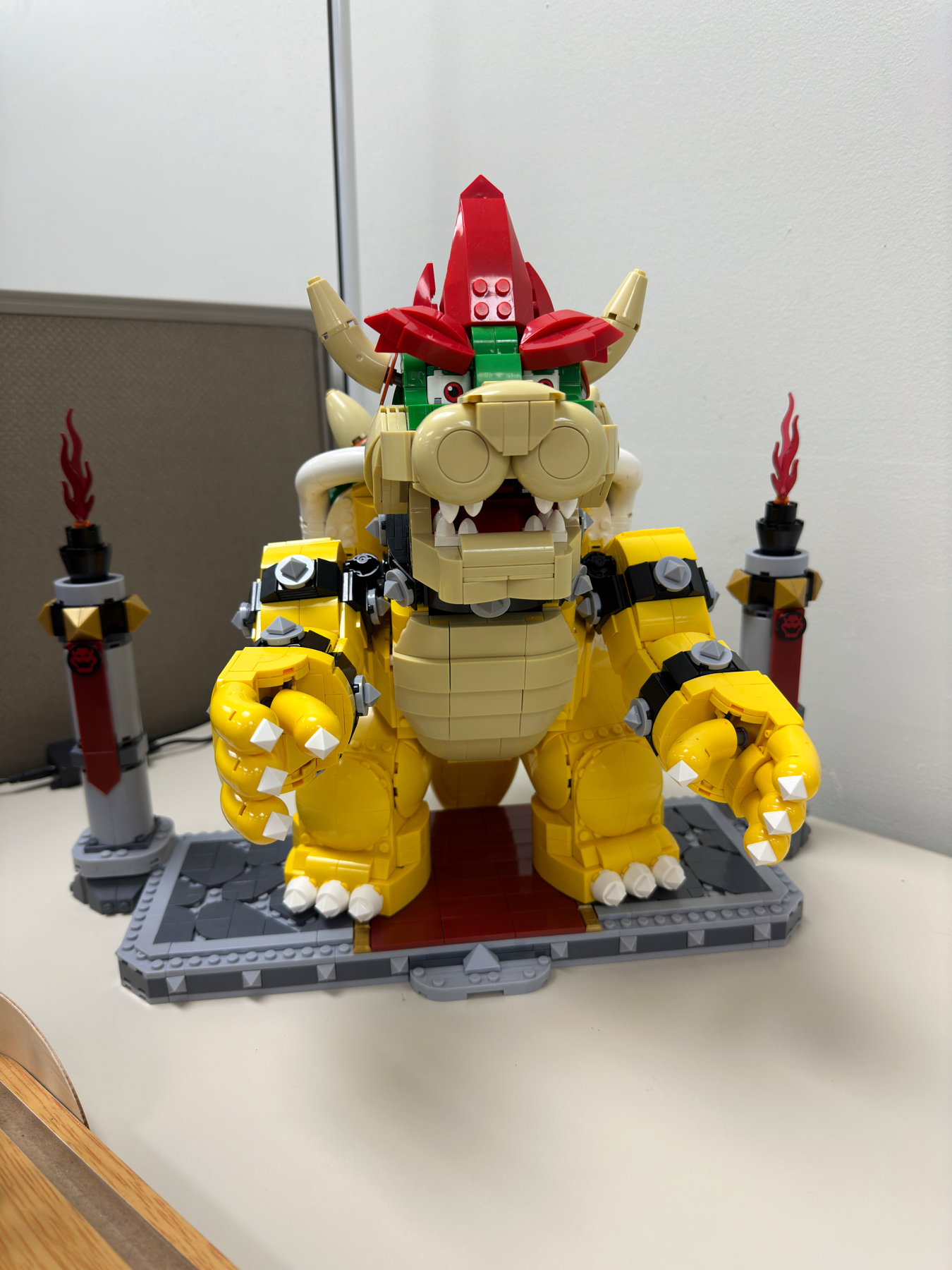 A LEGO model of a yellow and red dragon displayed on a desk, with brick-built flames on either side of the base platform.