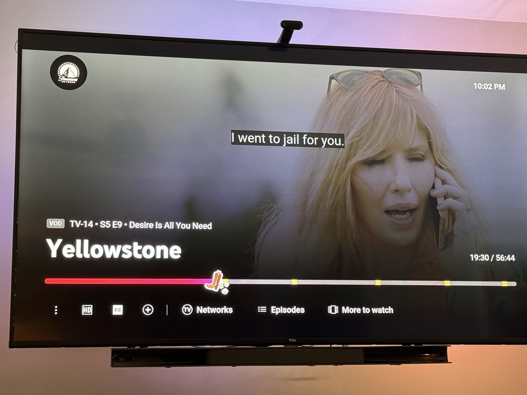 A TV screen displays a scene from "Yellowstone" Season 5, Episode 9, with subtitles reading "I went to jail for you."