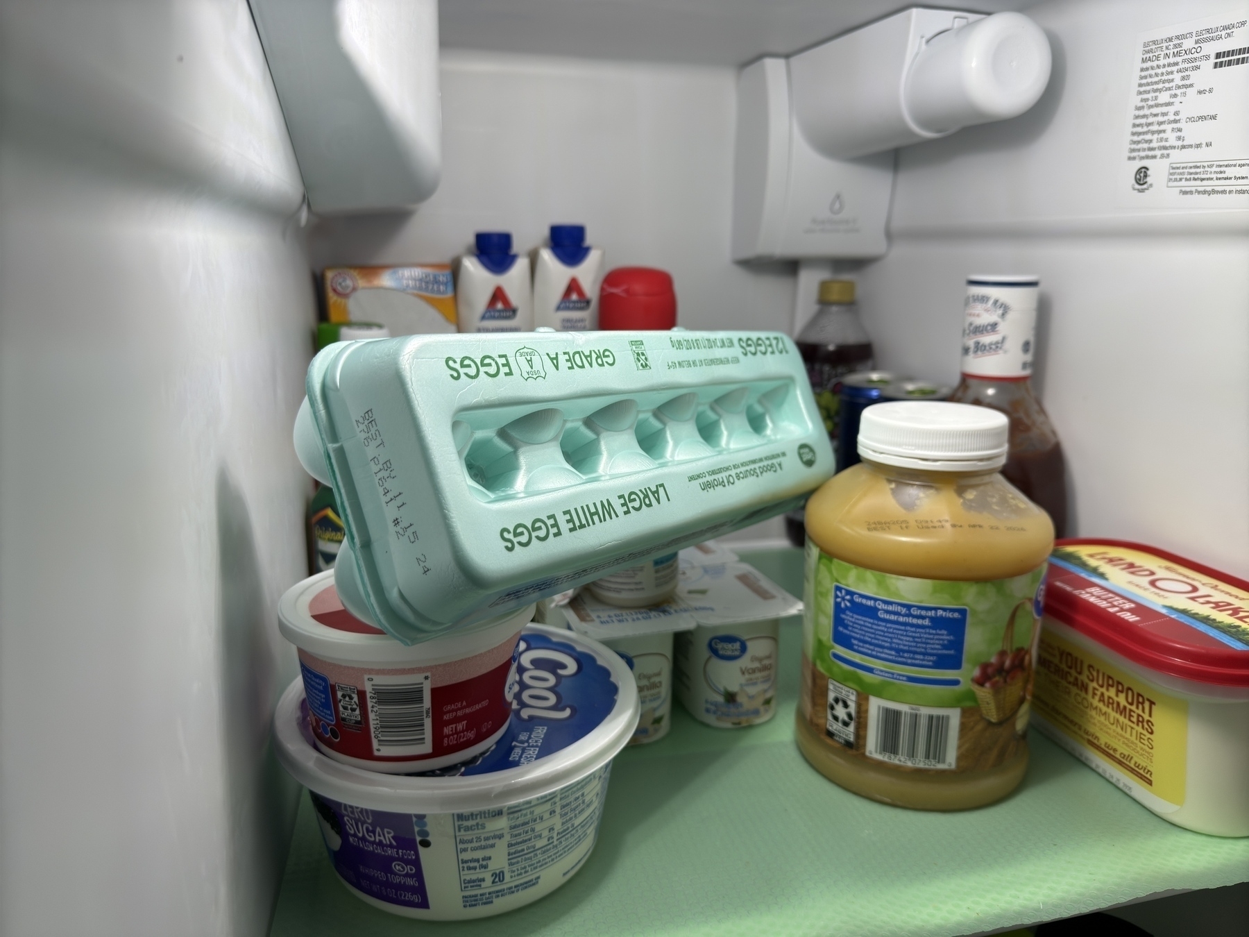 A refrigerator shelf contains a carton of eggs, containers of Cool Whip, juice, condiments, and other items.