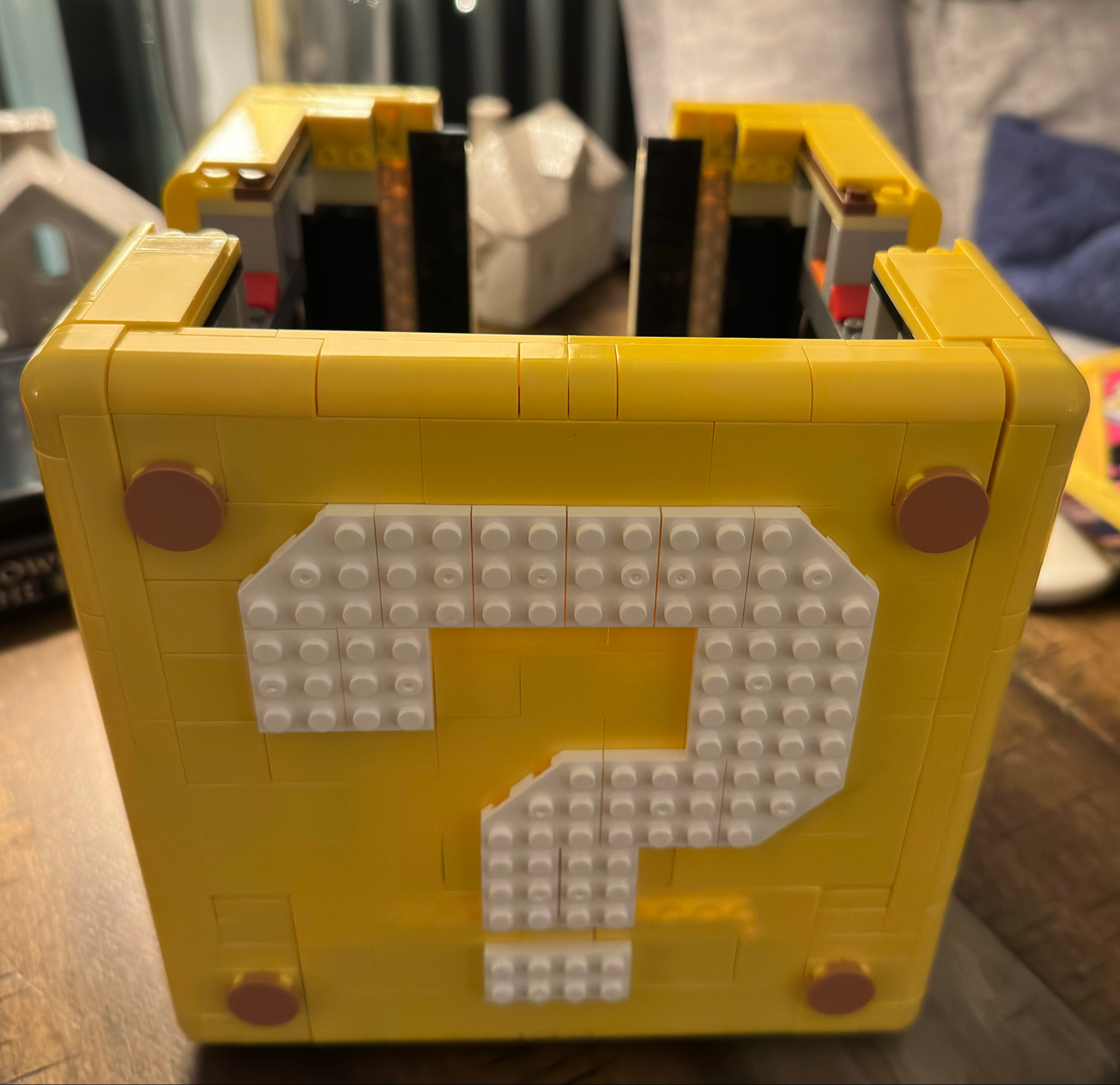A yellow storage box made of interlocking toy bricks with a 3-dimensional white question mark design on the side.
