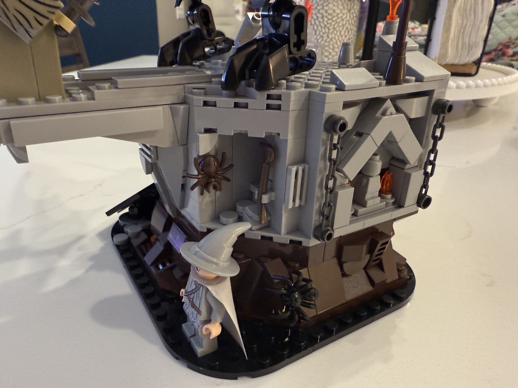 A Lego scene features a wizard figure next to a fortress wall adorned with spiders and weapons.