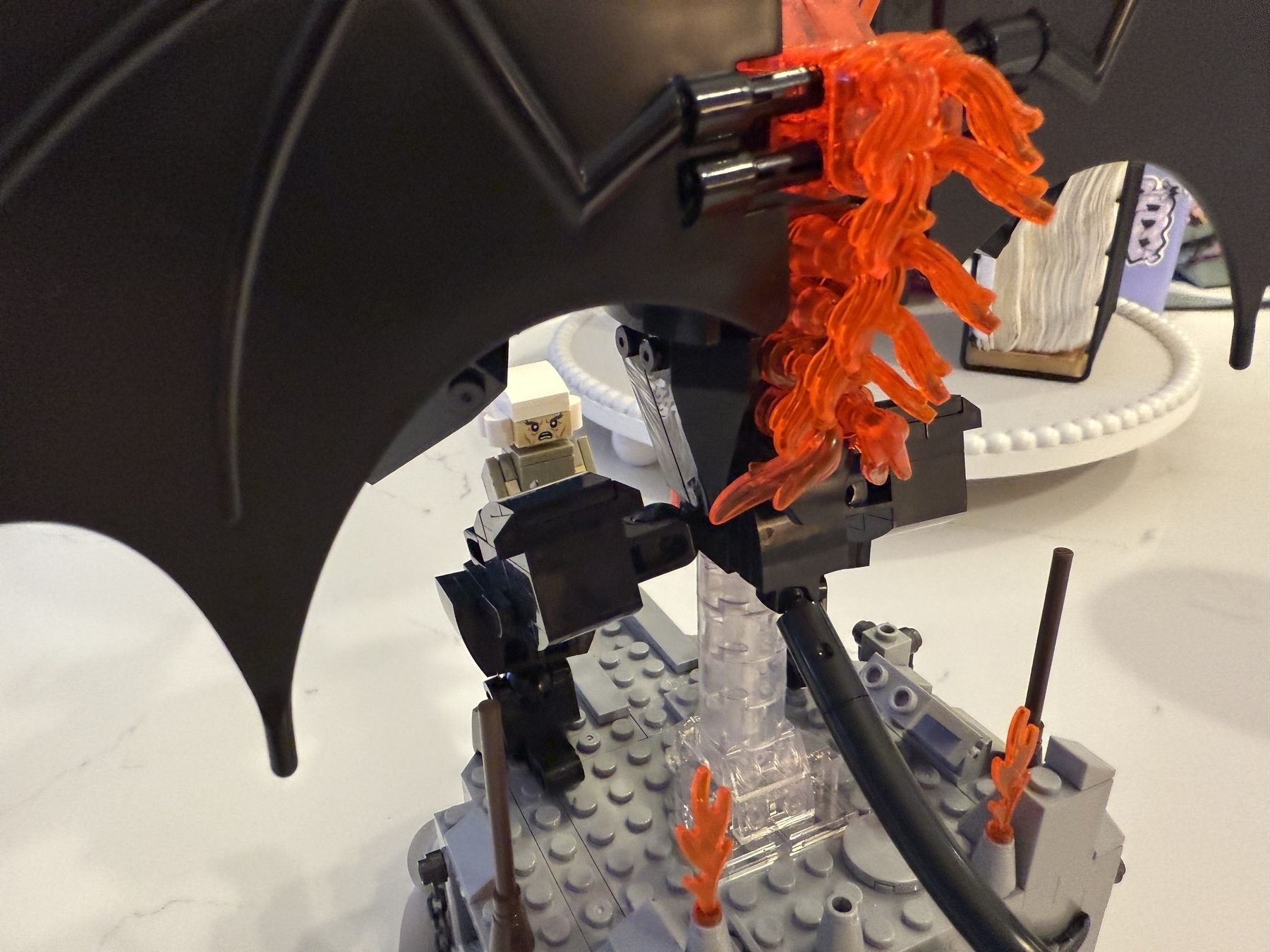 A LEGO scene features a dragon-like creature with fiery orange flames and a blocky terrain.