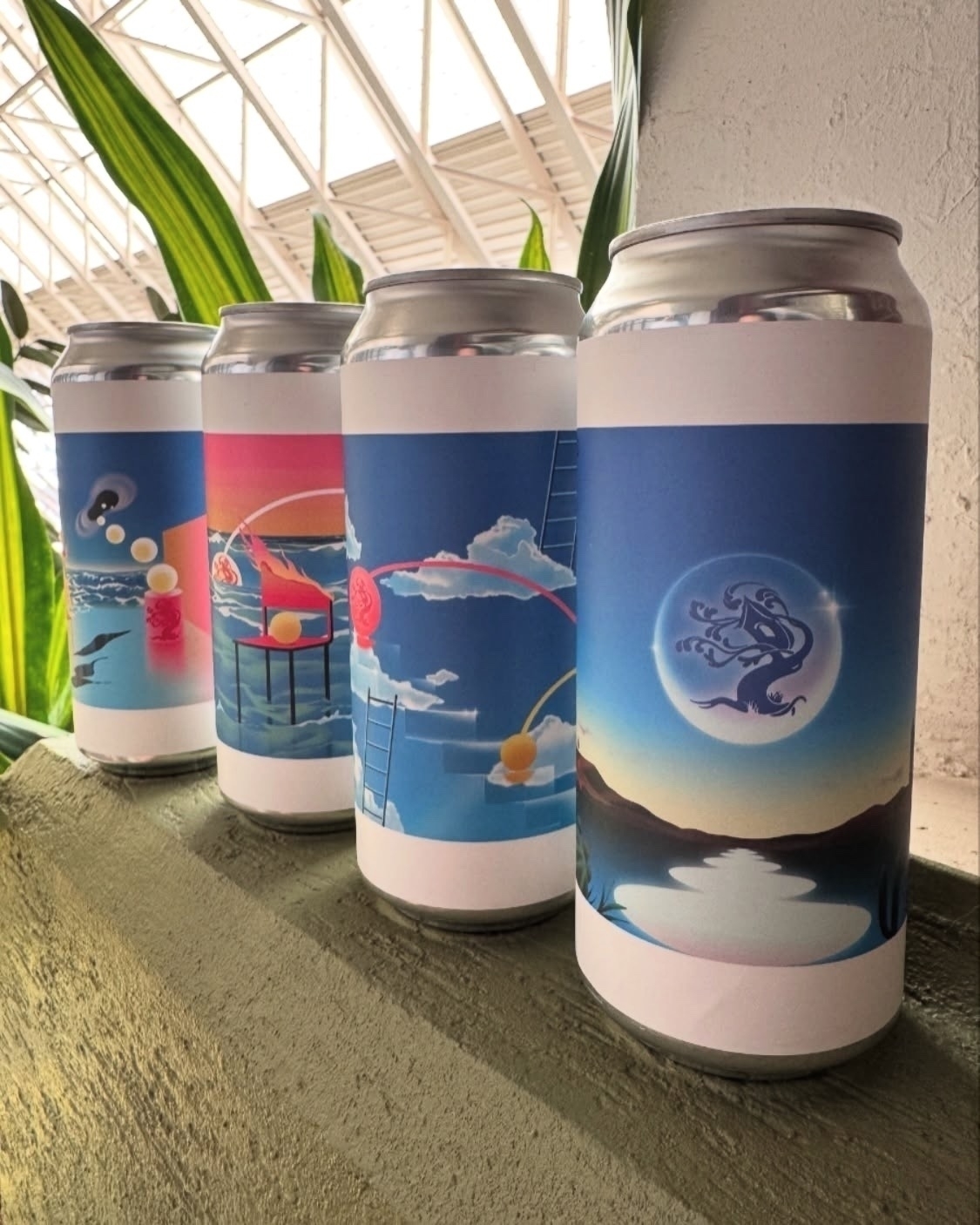 Four artfully designed beverage cans are displayed in a line, each featuring vibrant surrealistic illustrations.