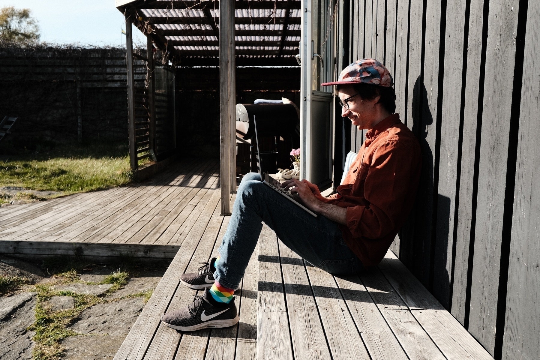 Johan, sittandes på ett trädäck, i solen, med en laptop.