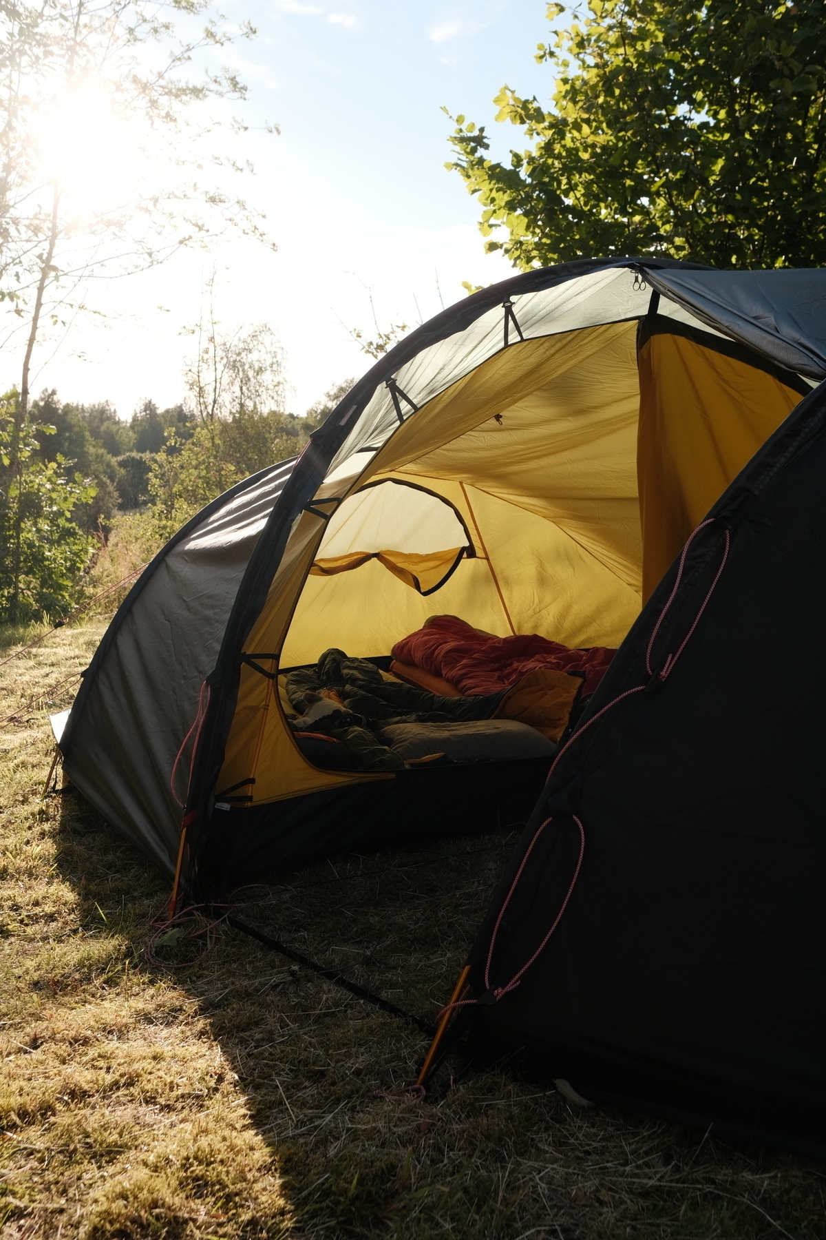 Ett tält i motljus med uppbäddade sovsäckar. 
