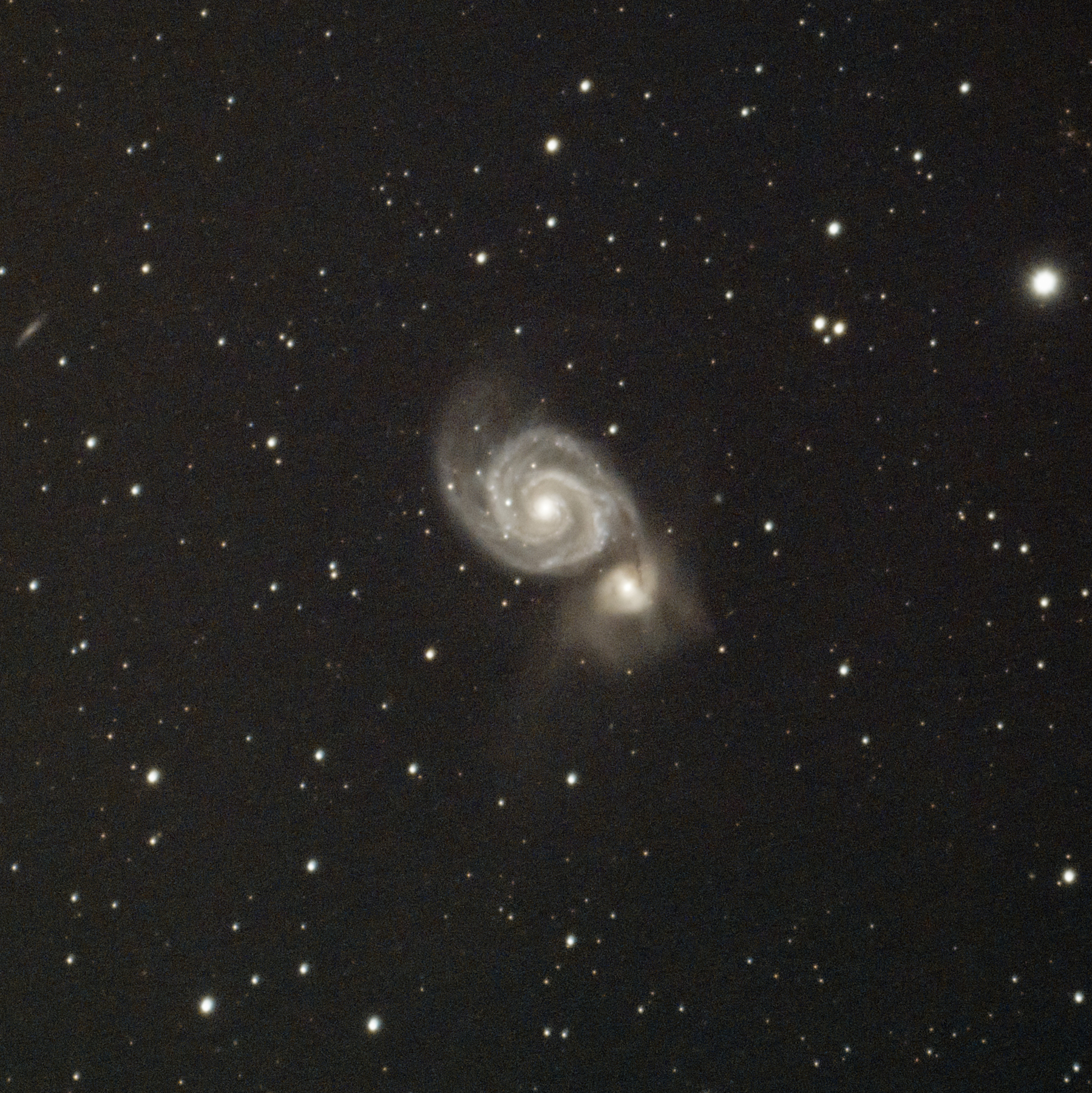 a face-on view of a spiral galaxy with its smaller companion on a dark star filled background