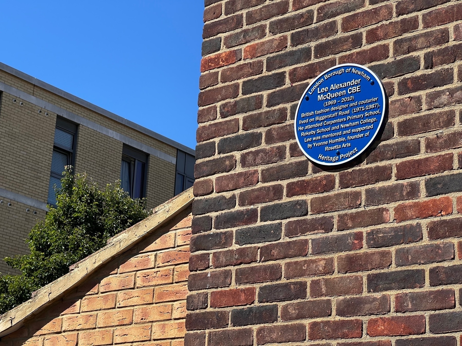 The text of the plaque: Lee Alexander&10;McQueen CBE&10;(1969 - 2010)&10;British fashion designer and couturier lived an Biggerstaff Road (1971-1987), He attended Carpenters Primary School, Rokeby School and Newham College, Lee was mentored and supported by Yvonne Humble, founder of&10;Rosetta Arts