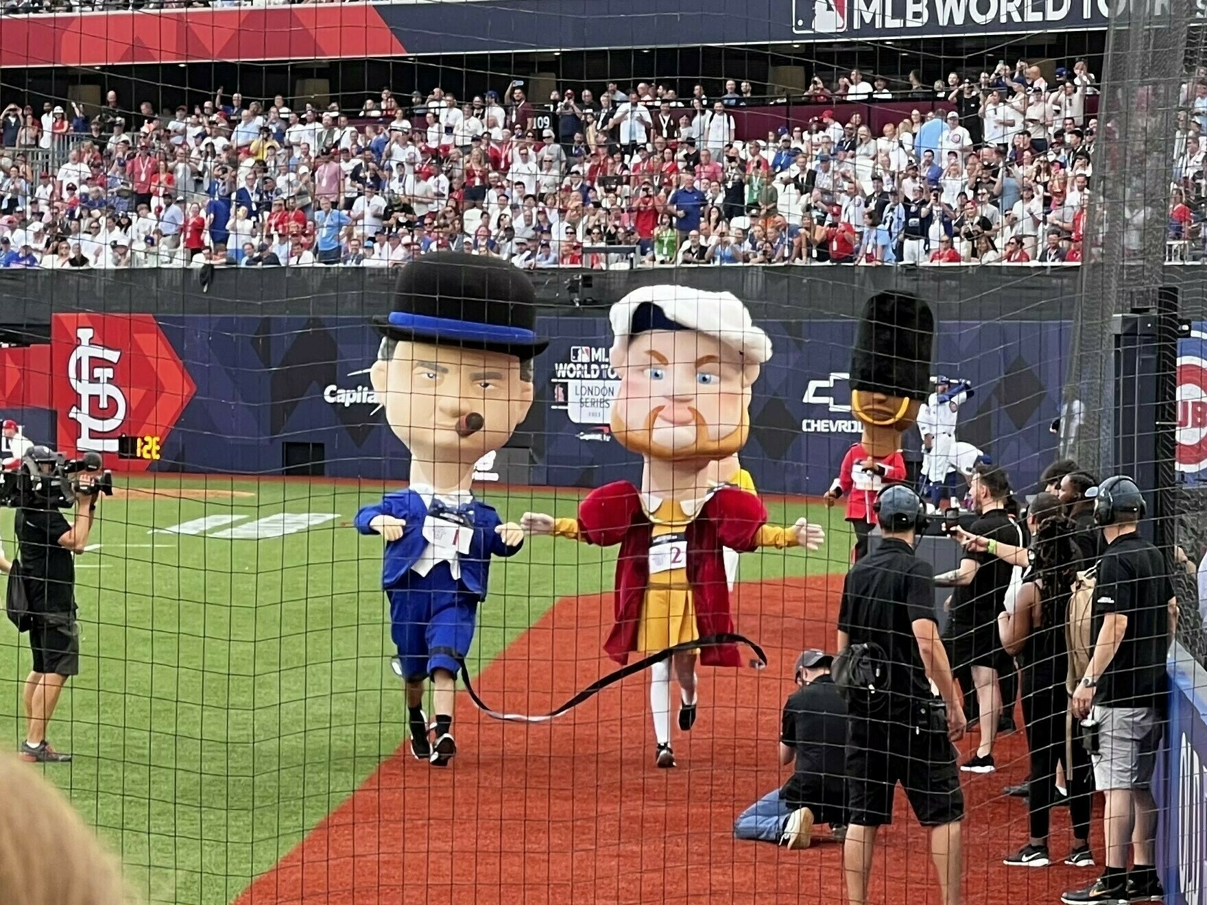 A mascot race at the MLB game in London. King Henry VIII edges out Winston Churchill with a royal guard some way behind.