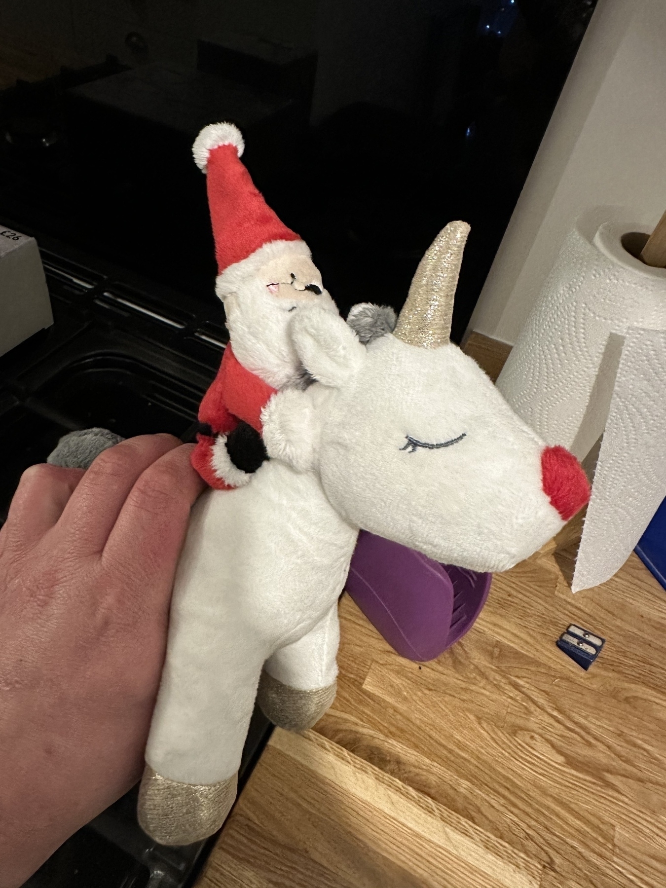 A plush toy of Santa riding a reindeer that is also a unicorn 
