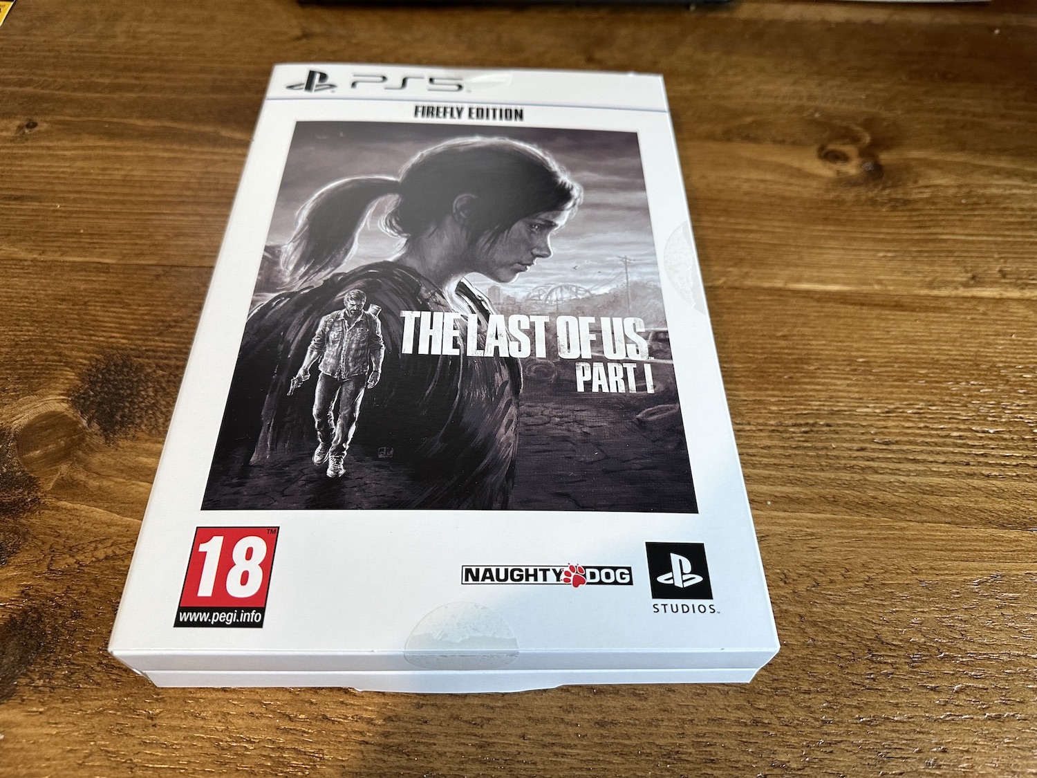 A white carboard box with the cover art for The Last of Us on the front