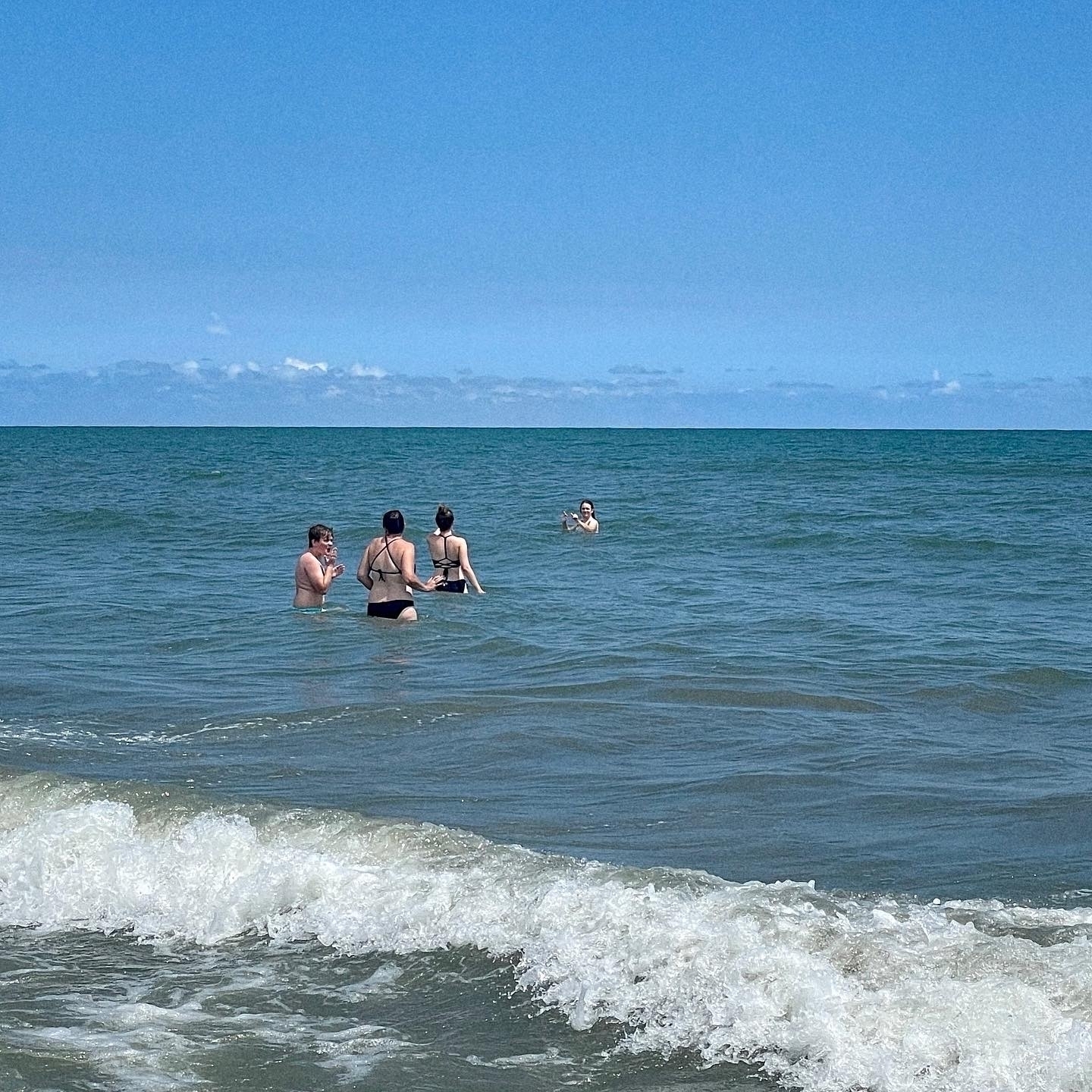 Four people in the water at the beach. 