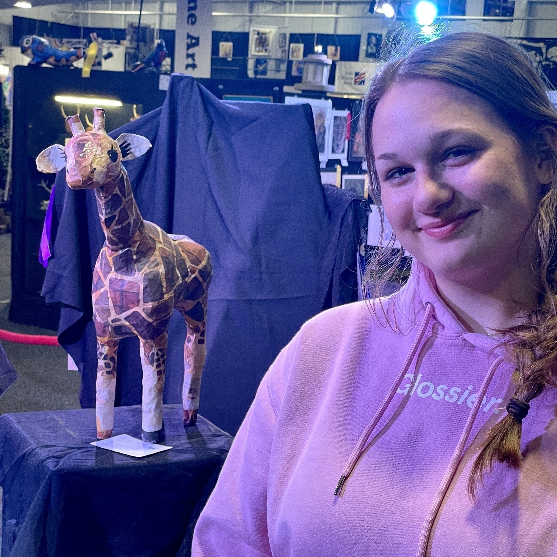 Jill smiles next to a crafted giraffe model displayed at the SC State Fair. 