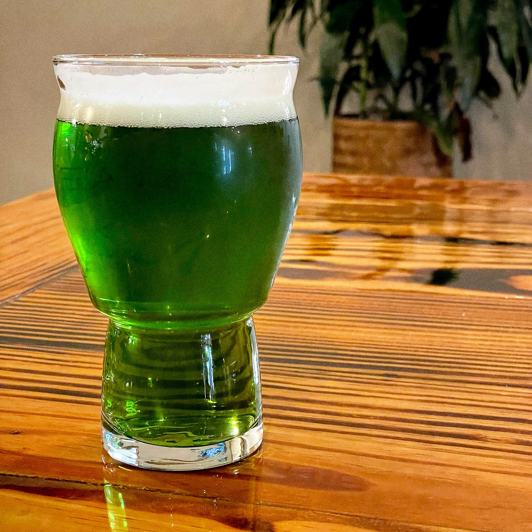 Green beer on a wooden table. 