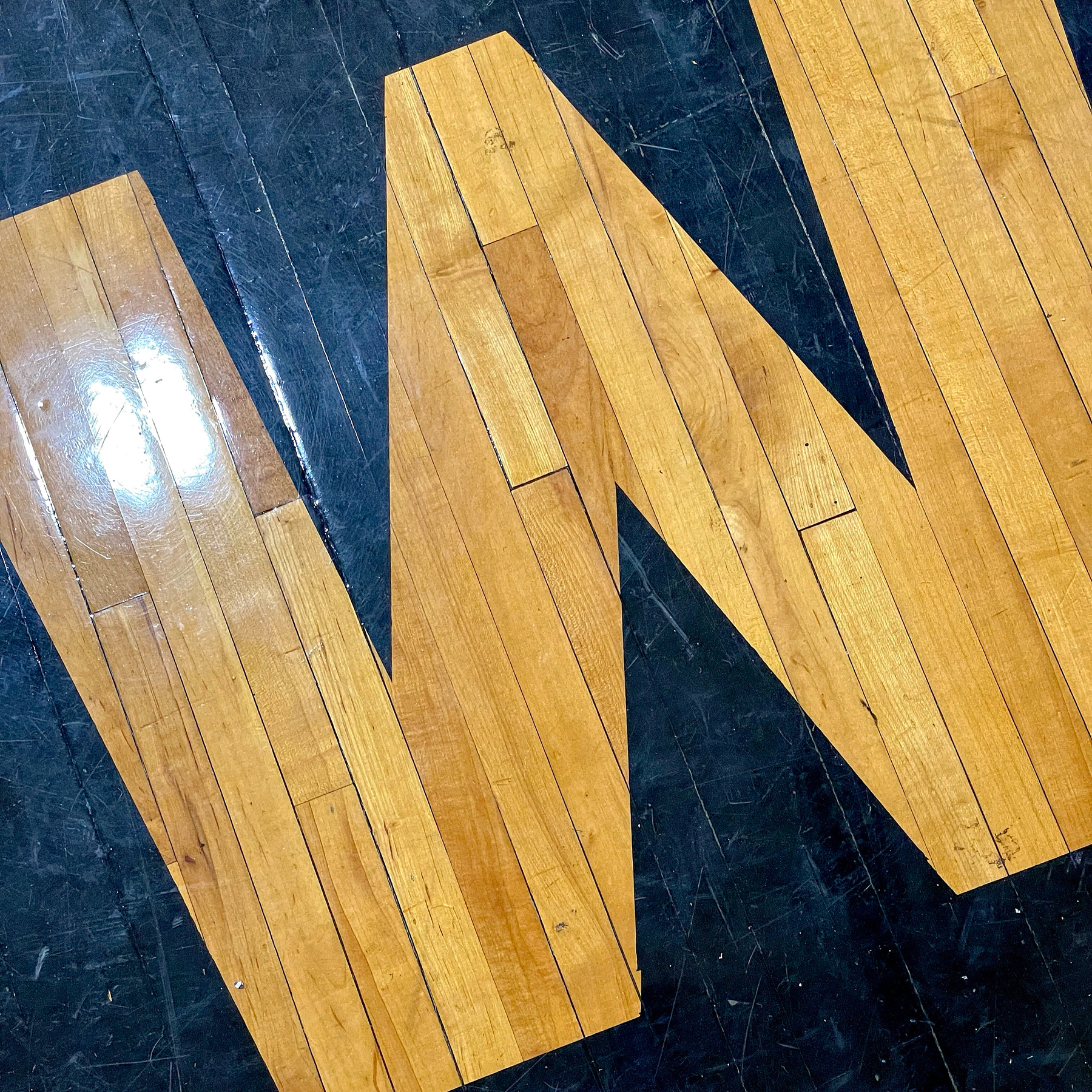 Letter W painted on an old gym floor. 