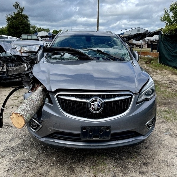 SUV in junkyard impaled by a tree.