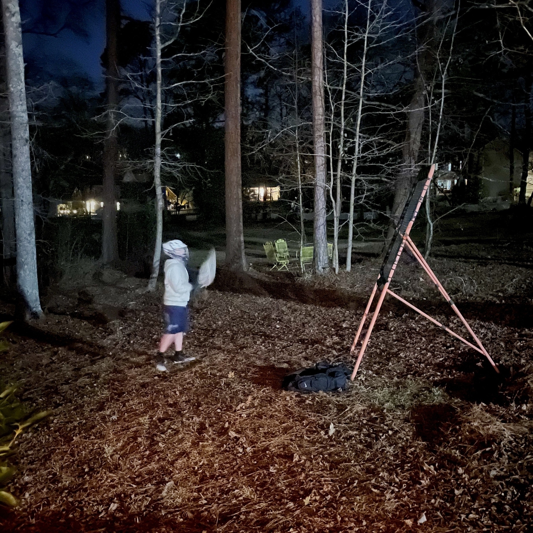 Boy in back yard practicing lacrosse. 