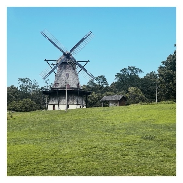 Old windmill at the top of a grassy hill.